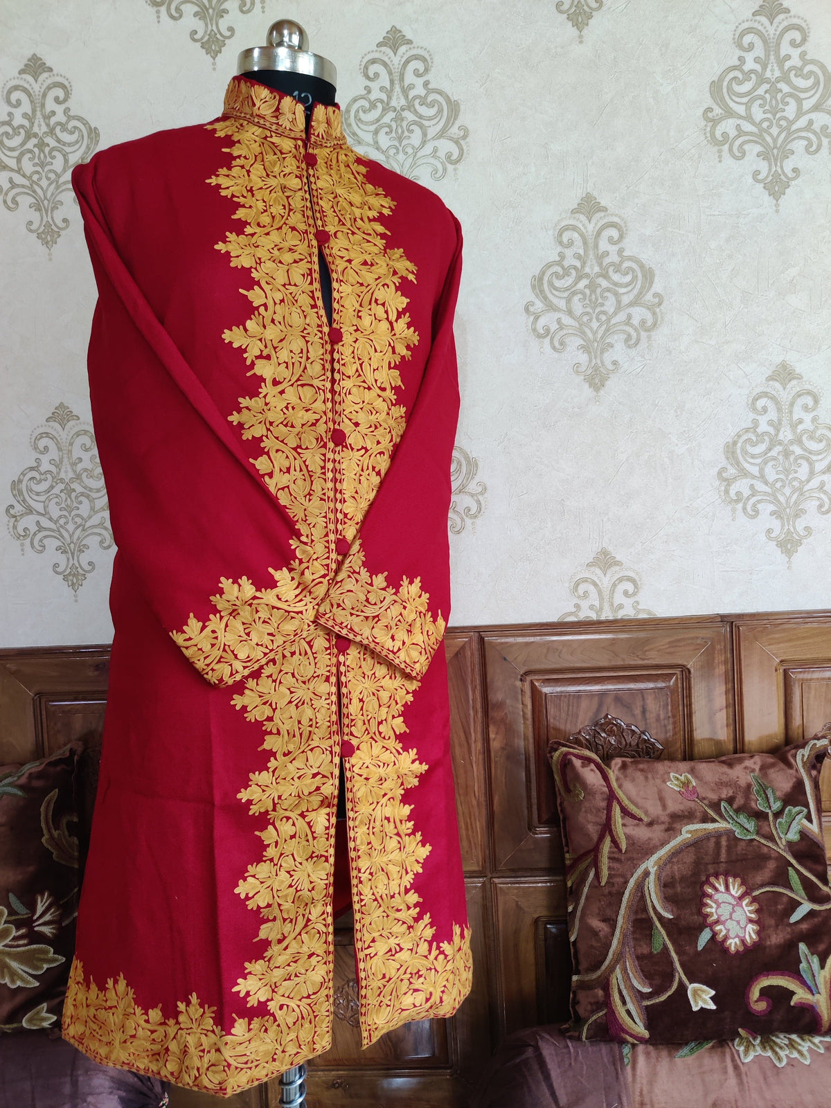 Three-quarter front of the maroon Aari jacket on a mannequin, showing floral borders at the collar, opening, cuffs and hem.