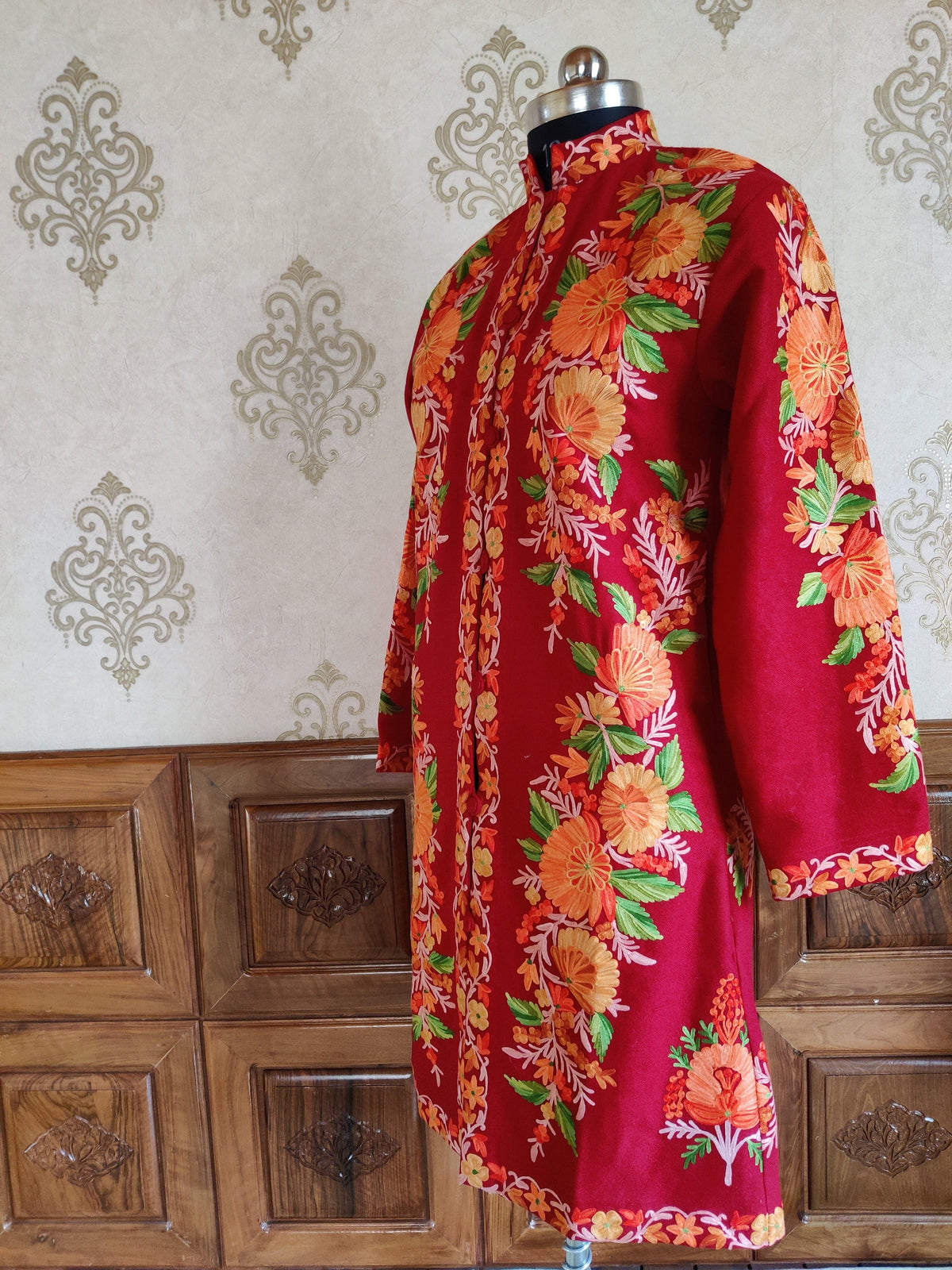 Full-length angled front view of a maroon jacket with orange and peach flower trails along the opening and sleeves.