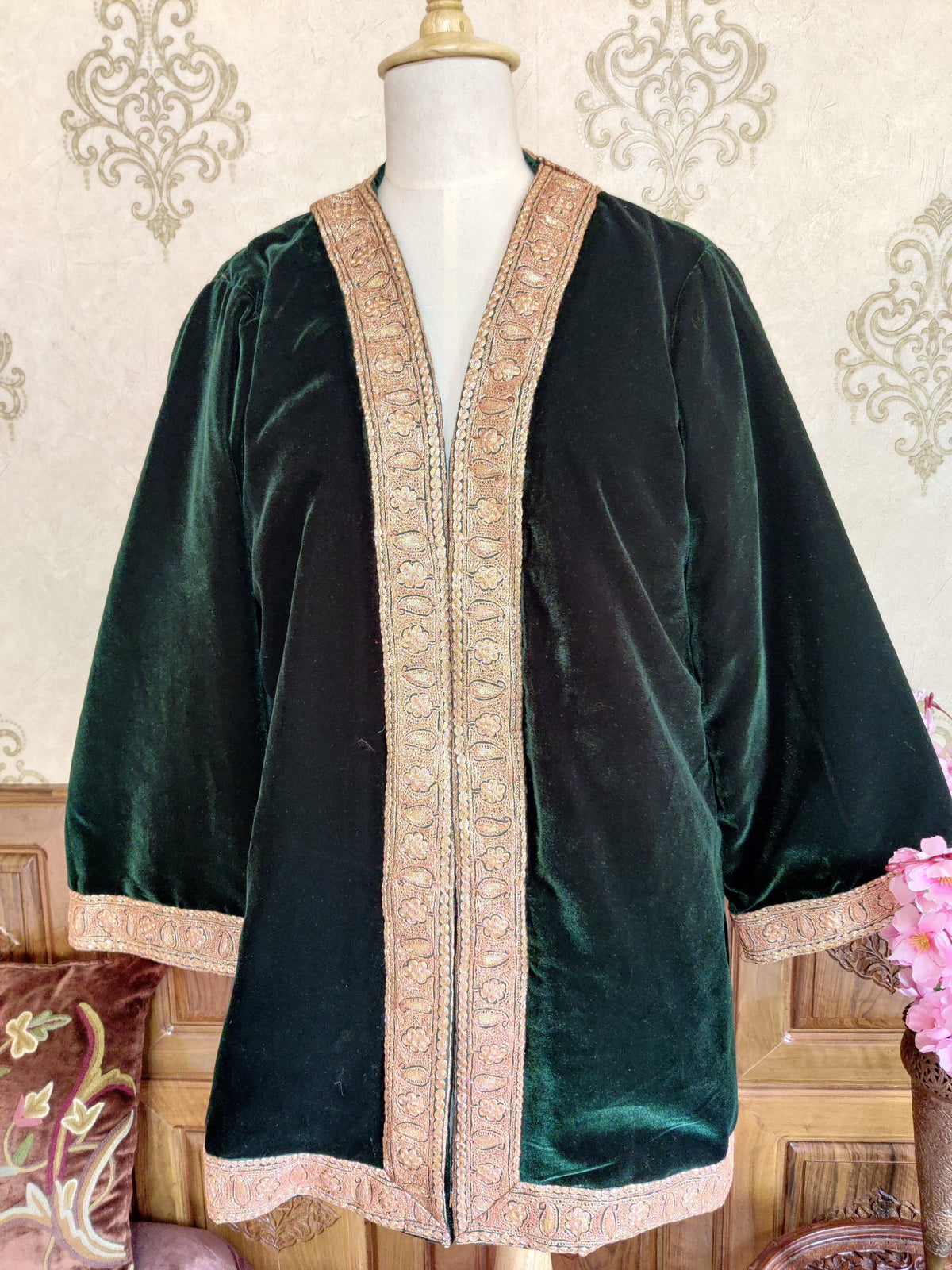 Front of a dark green kimono robe on a mannequin, with wide sleeves and gold-toned Tilla floral edging around the opening, cuffs and hem.