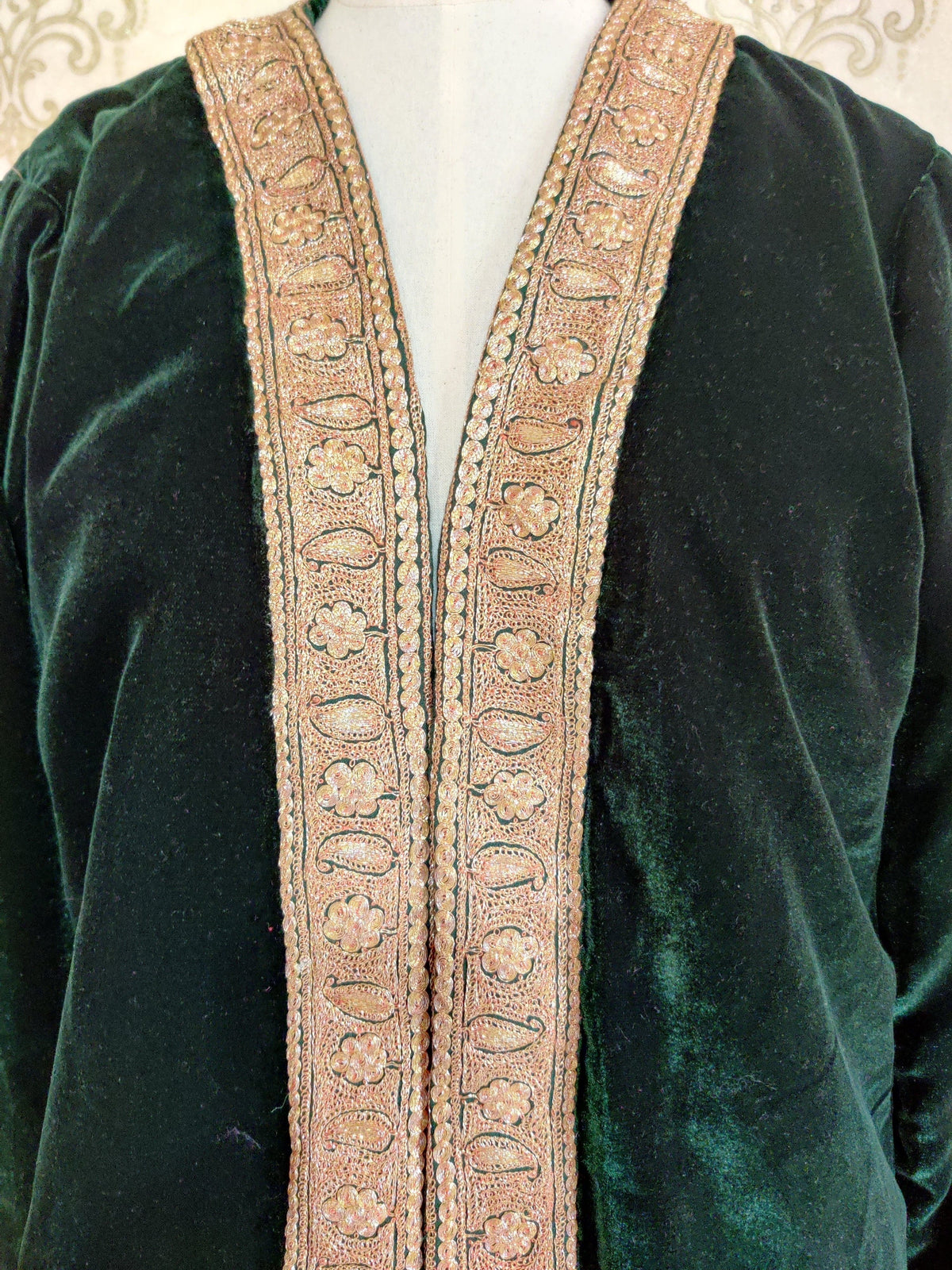 Close-up of the dark green robe's front opening, with two gold-toned Tilla bands of small flowers and oval leaf shapes.