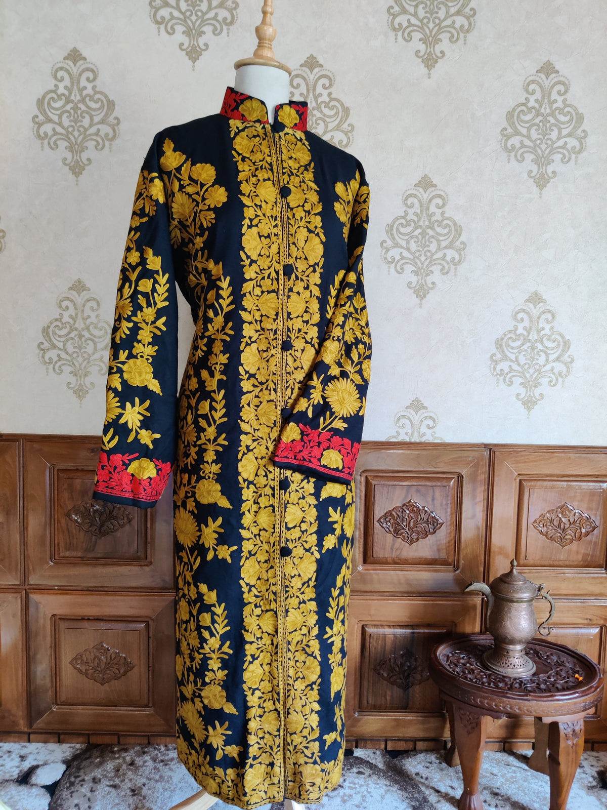 Full-length front view of a navy jacket with mustard-yellow floral embroidery and red accents at the collar and cuffs.