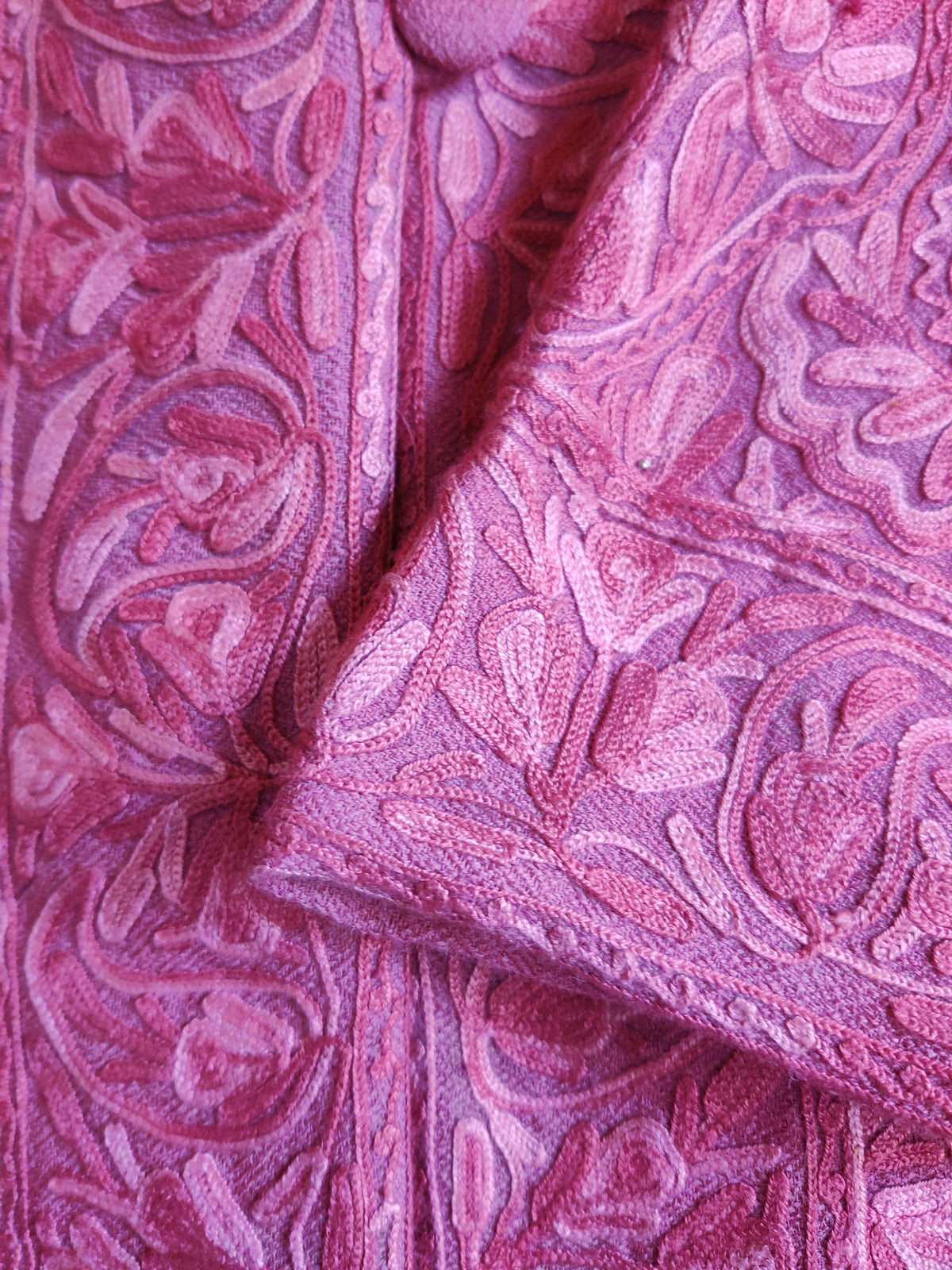 Closer view of the folded pink cuff and jacket front, with raised tonal Aari leaves and floral scrolls.
