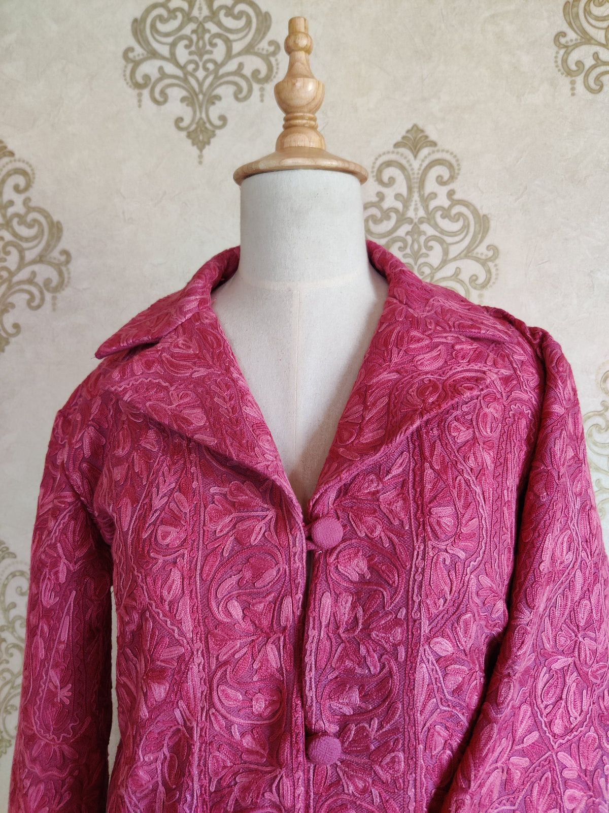 Upper front of the pink jacket, showing the notched collar, covered buttons and tonal Aari embroidery.