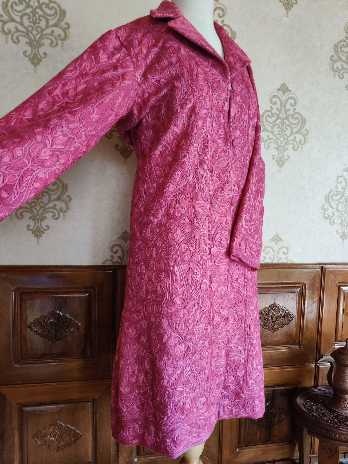 Angled view of the pink Aari jacket with one sleeve extended, showing tonal floral embroidery across the sleeve and side.
