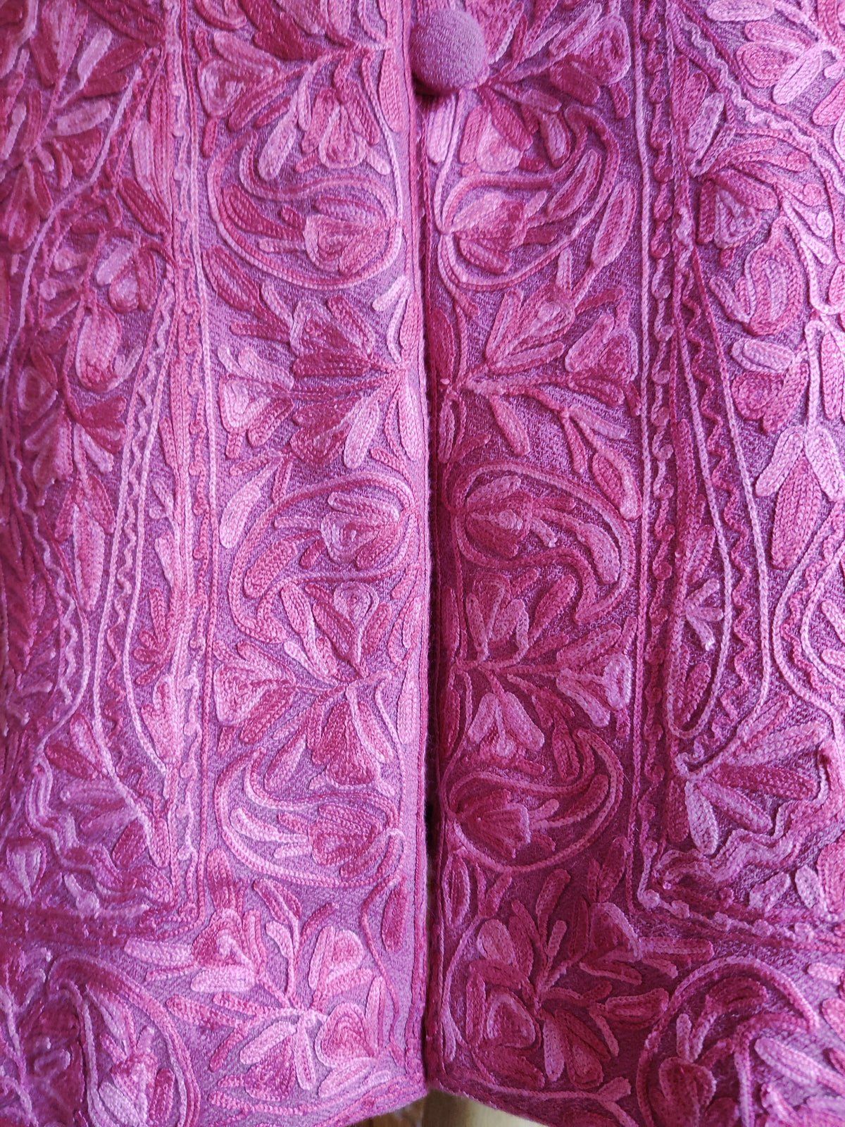 Close-up of the pink jacket’s lower front, showing tonal Aari floral scrolls and a narrow embroidered border near the hem.