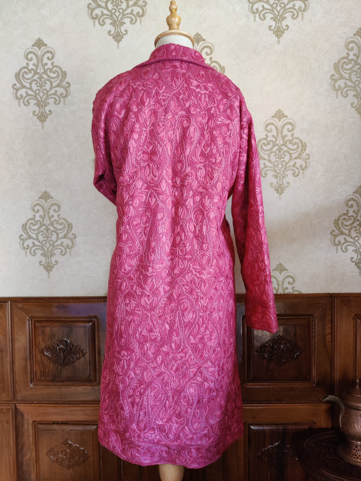 Full back of the long pink jacket on a mannequin, covered in tonal Aari floral and paisley embroidery.