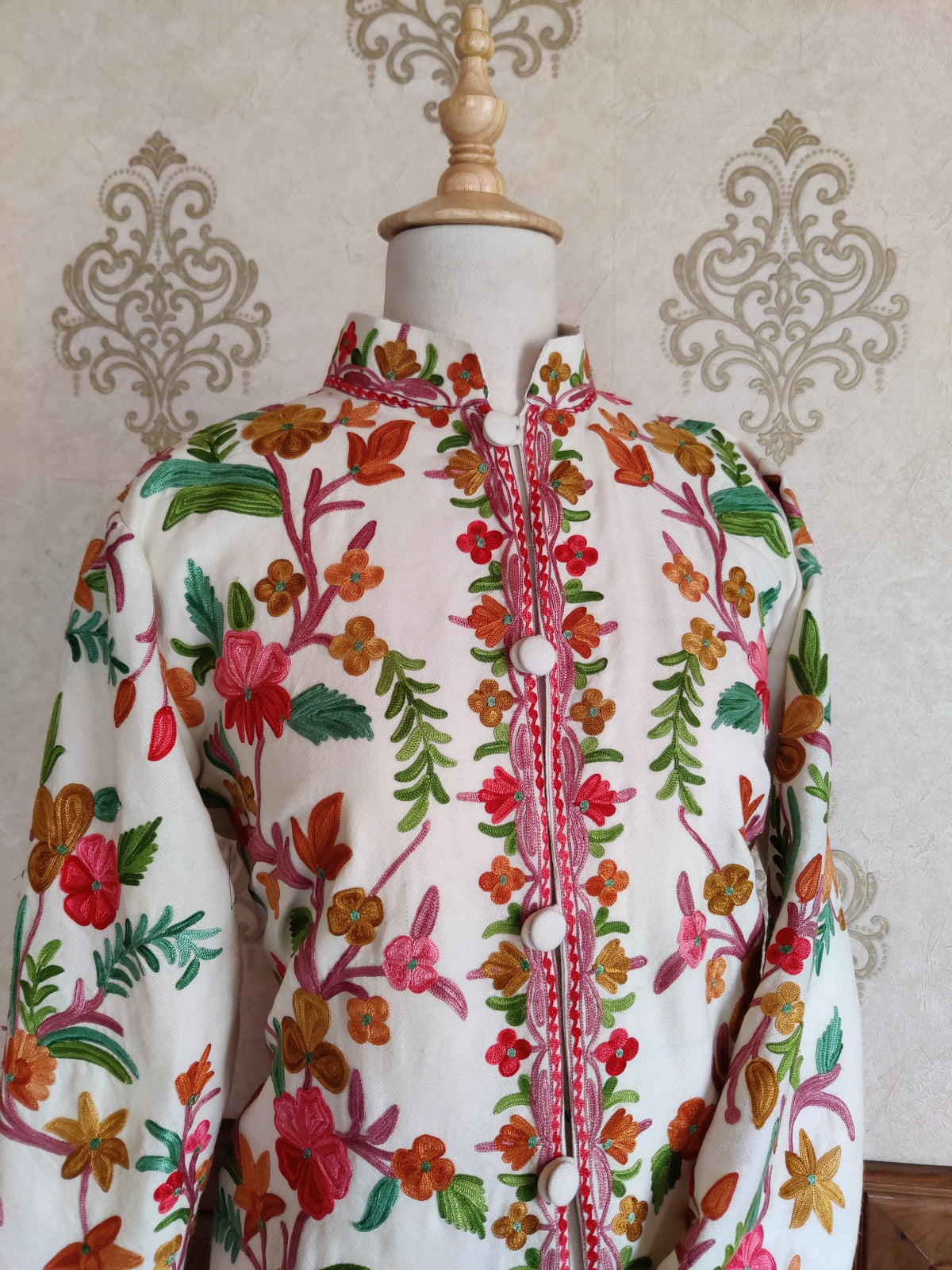 White Aari jacket stand collar and upper front with multicoloured floral vines, pink trim and white covered buttons
