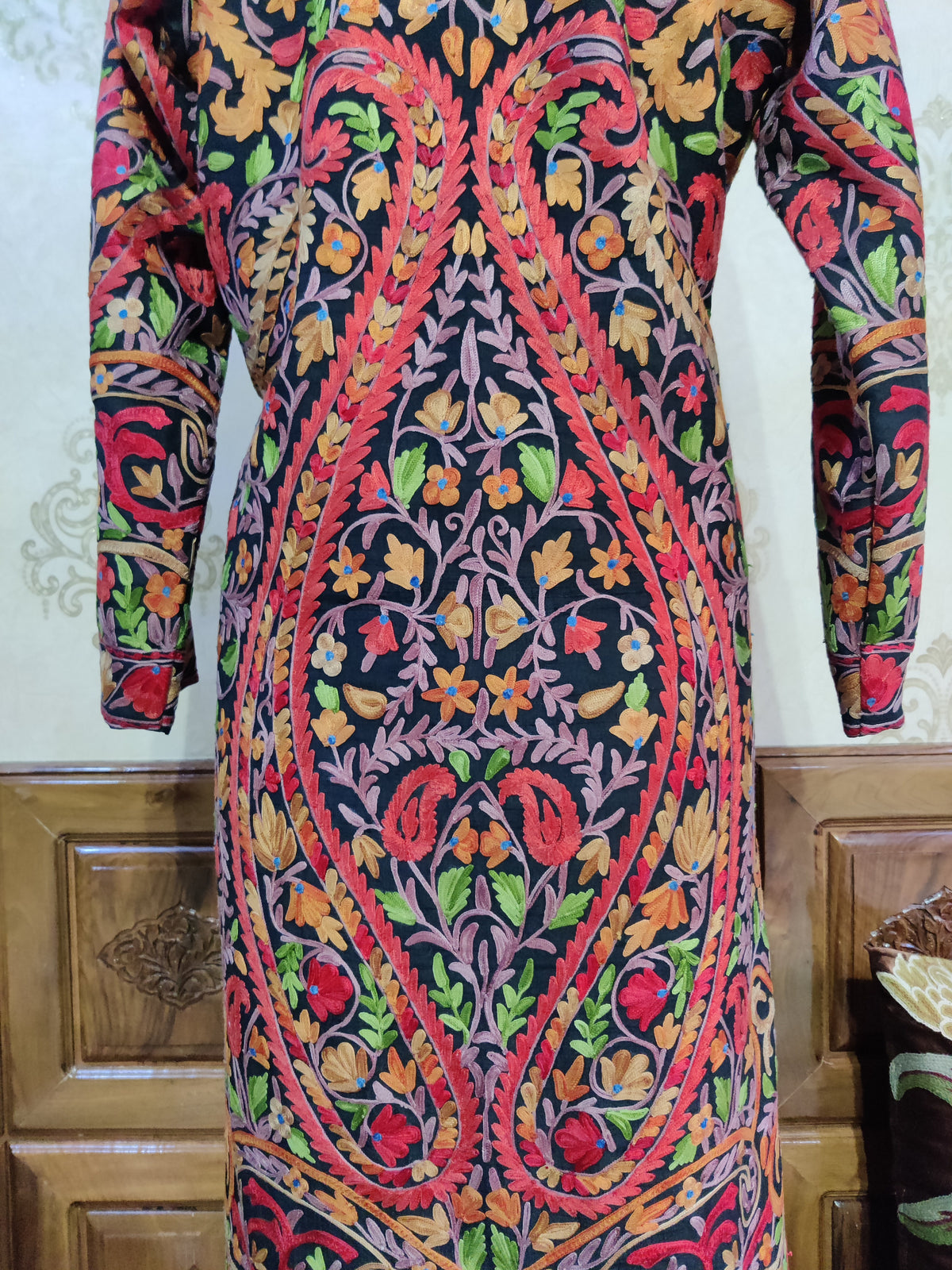 Closer back of the black Aari jacket, showing two sweeping red-edged paisleys enclosing a dense arrangement of colourful flowers.