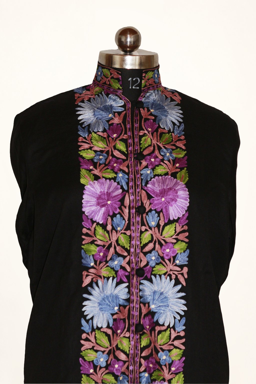 Front detail of a black jacket on a mannequin, with lilac and pale blue Aari flowers, pink stems and green leaves along the placket.