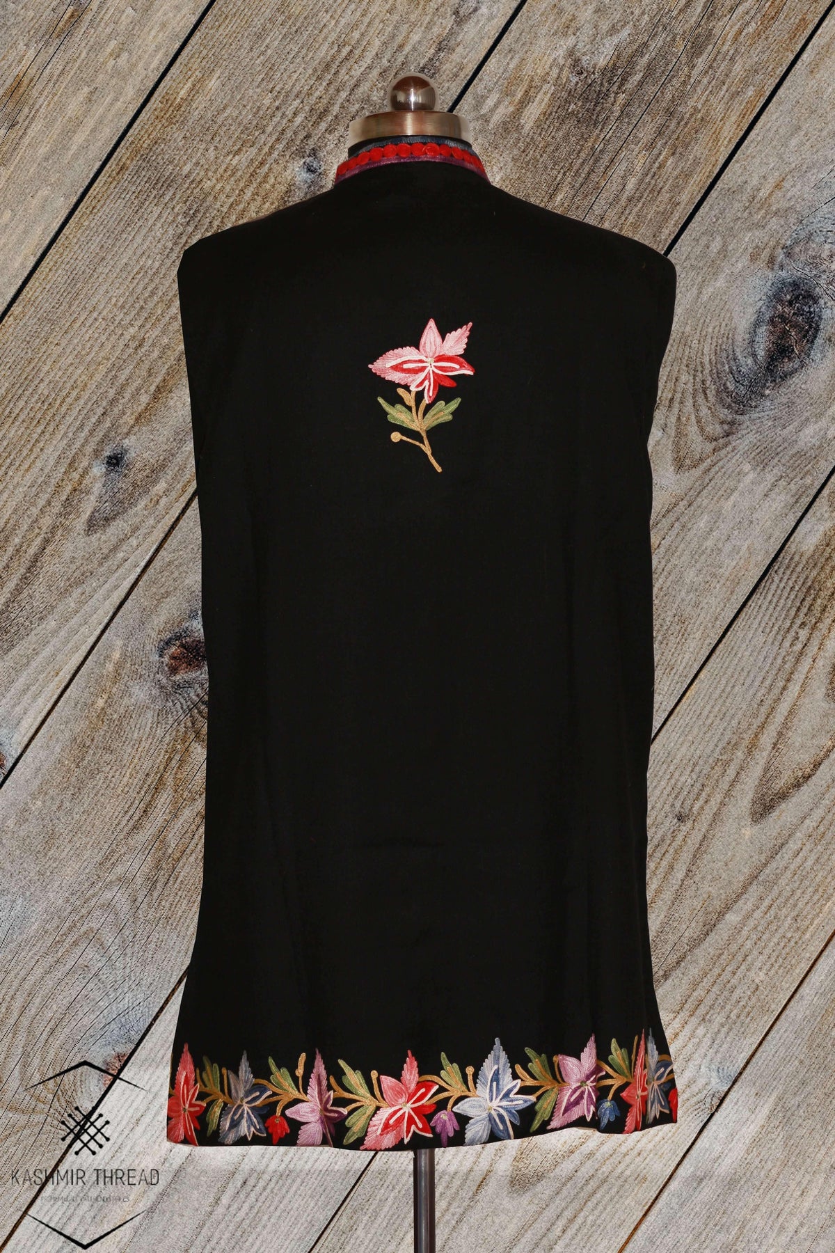 Back view of the black jacket, with a small pink Aari leaf sprig between the shoulders and multicoloured chinar leaves along the hem