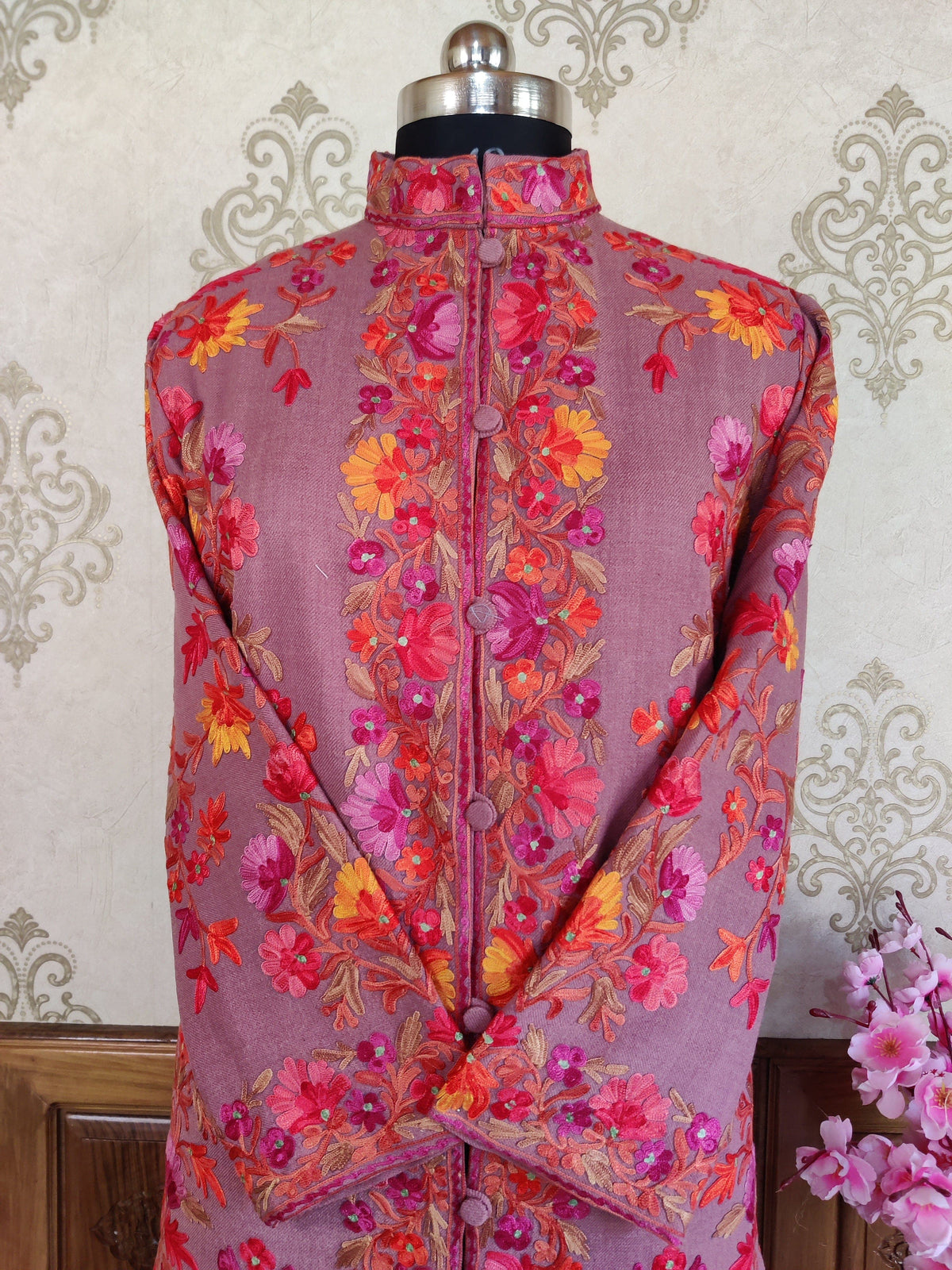 Upper front of a mauve coat with crossed sleeves, a stand collar and pink, orange and yellow Aari floral vines