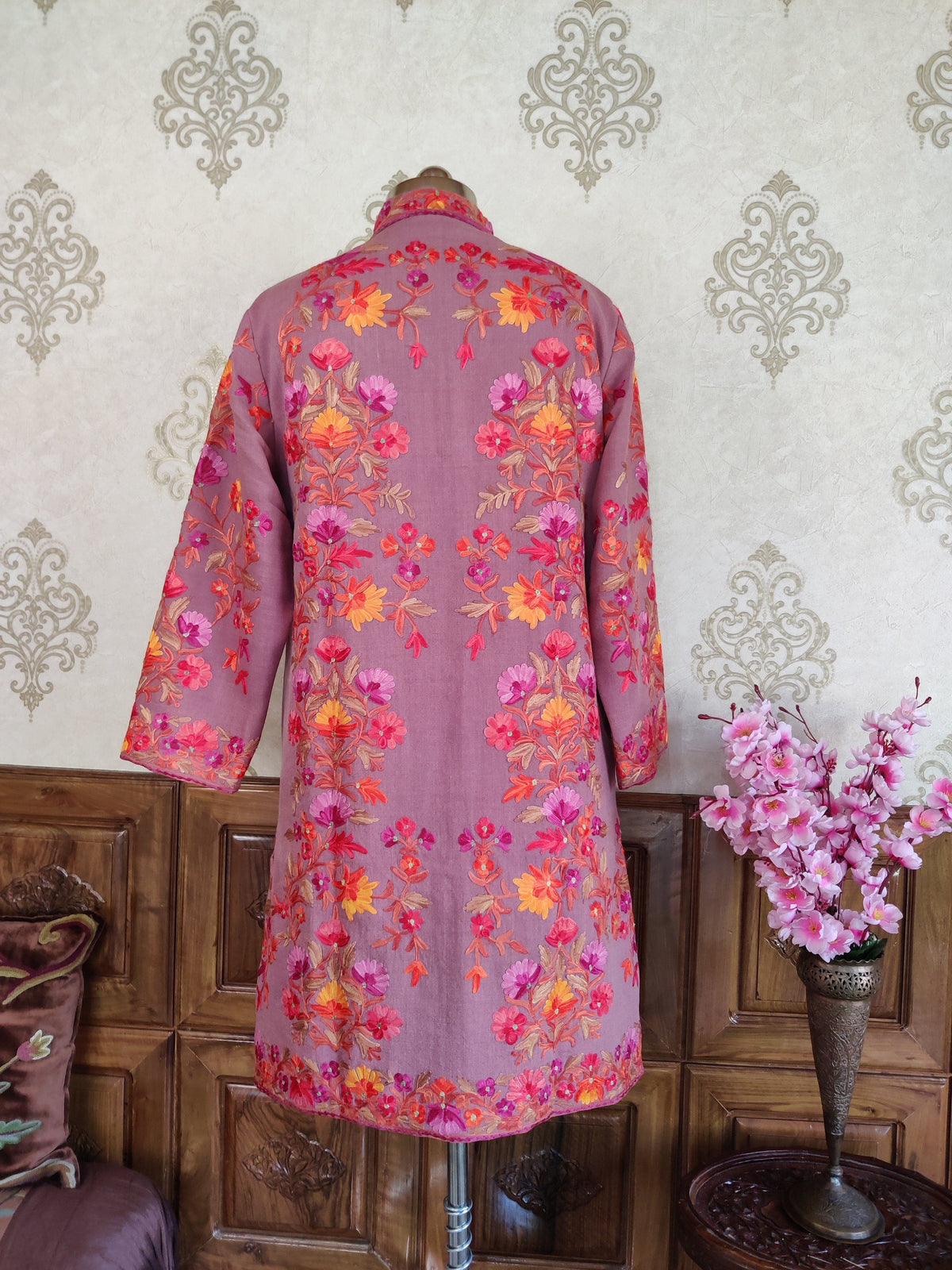 Back of a mauve long coat with symmetrical bright pink and orange Aari floral arrangements and a narrow flowered hem