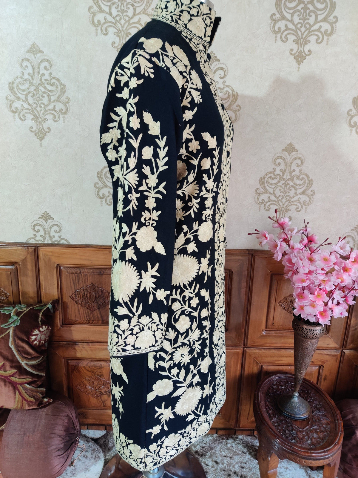 Side view of the black long jacket, showing white Aari flowers and leafy vines down the sleeve and side panel