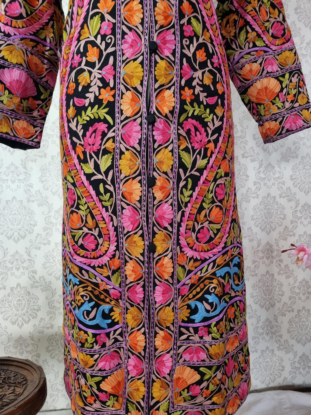 Front detail of the black jacket showing paired large paisleys and pink, orange and yellow flowers beside the fastening.