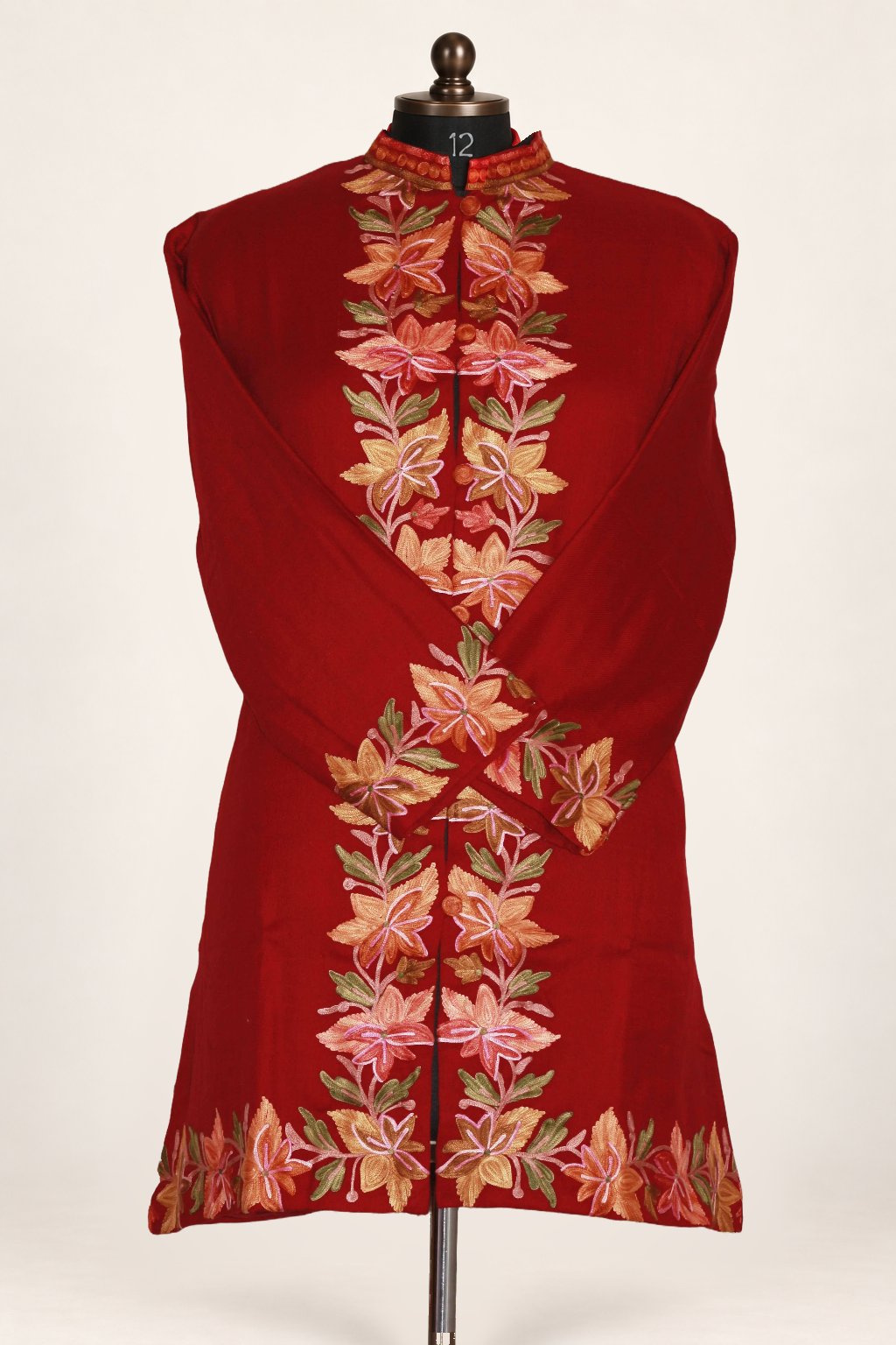Front view of a maroon jacket with peach Aari flowers along the front, cuffs and hem, shown with both sleeves crossed