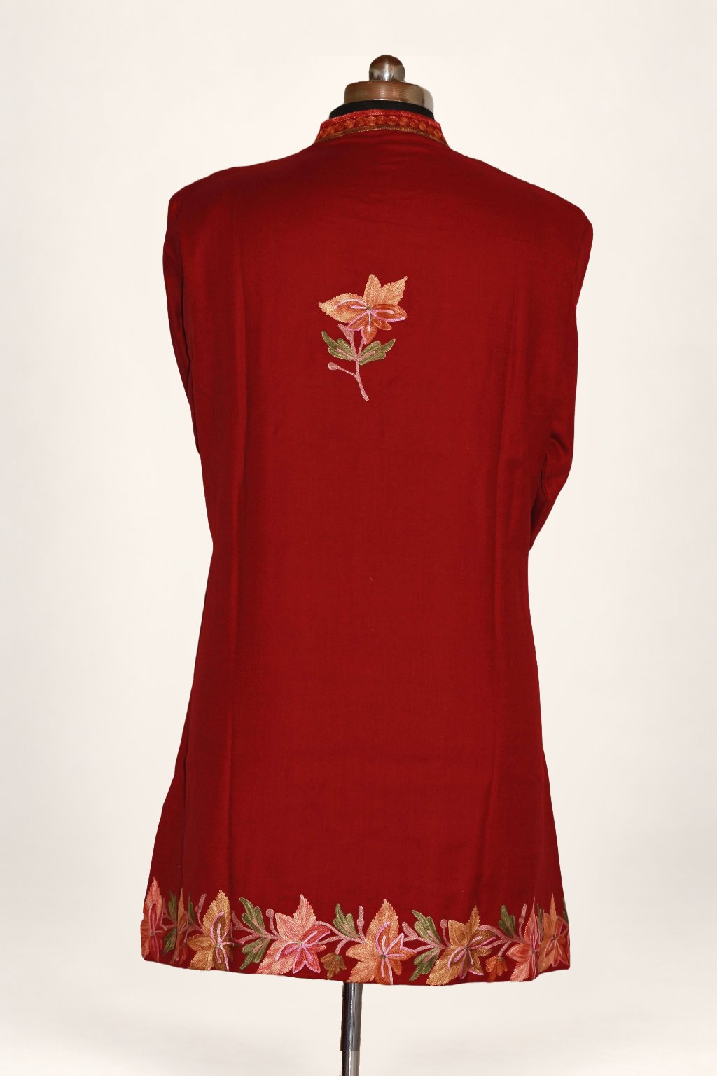 Back view of maroon jacket with a small Aari floral sprig between the shoulders and a colourful floral hem border