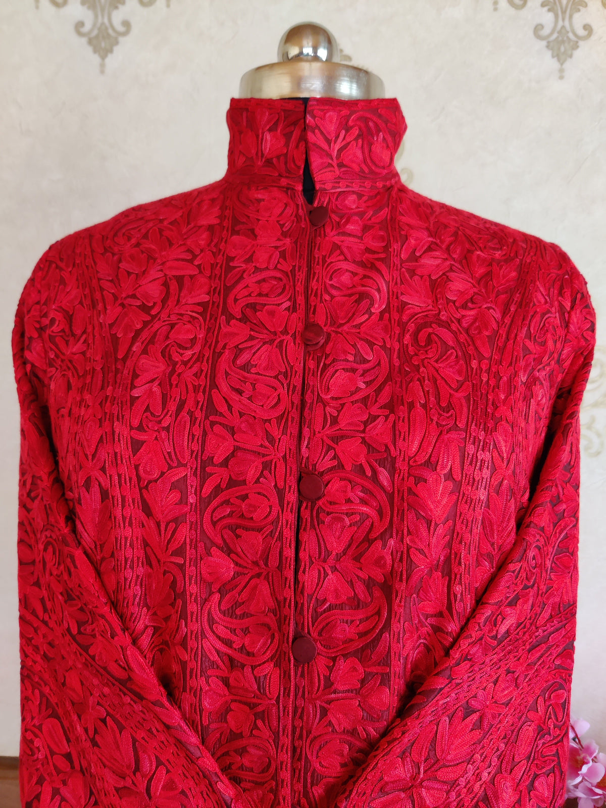 Upper-front close-up of red coat showing tonal Aari floral embroidery, standing collar and covered buttons