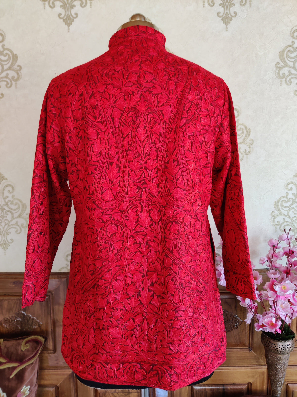 Back view of red coat covered in tonal Aari paisley and leafy embroidery with an embroidered hem border