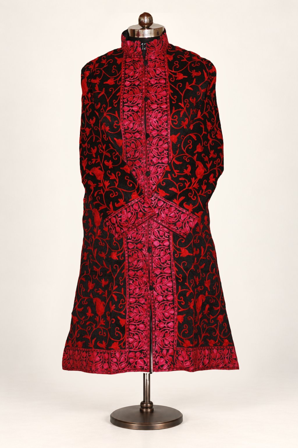 Front view of a black long coat with bright red Aari floral vines, broad pink-red borders and crossed sleeves