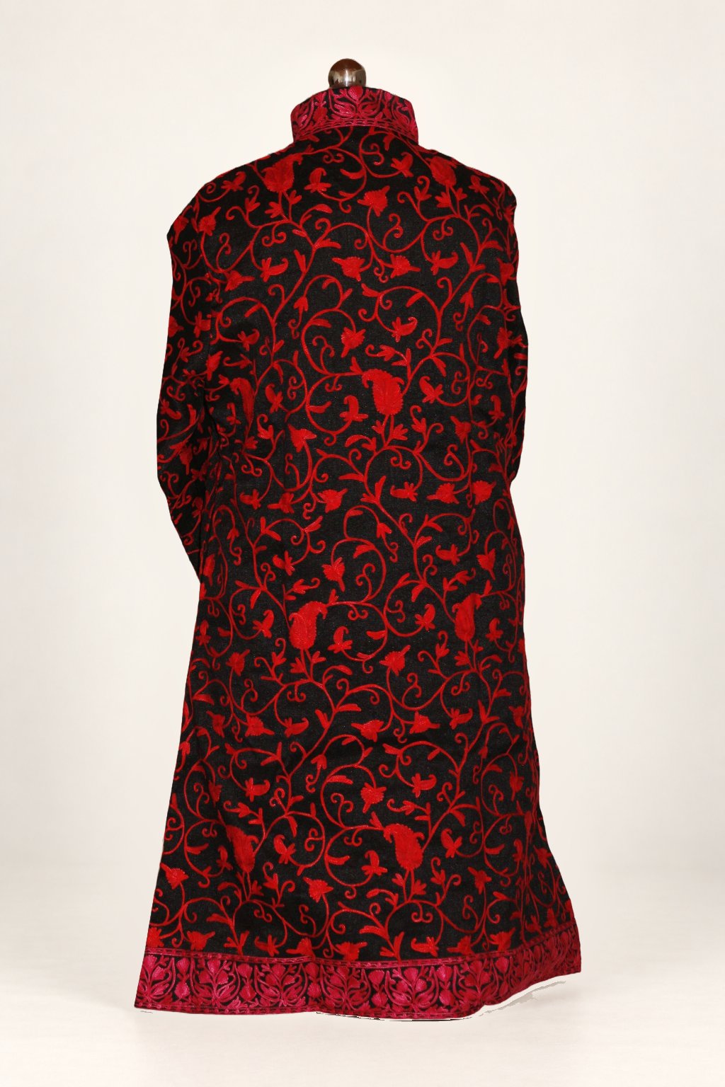 Back view of black long coat covered in red Aari floral vines, with a standing collar and broad embroidered hem border