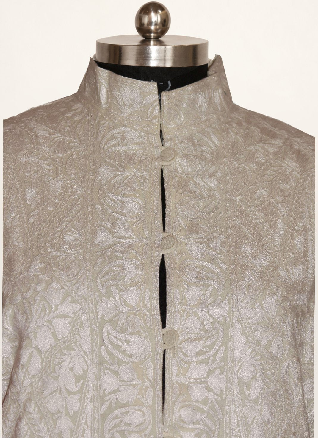 Front close-up of ivory-white long jacket with tonal Aari floral and paisley embroidery, standing collar and covered buttons