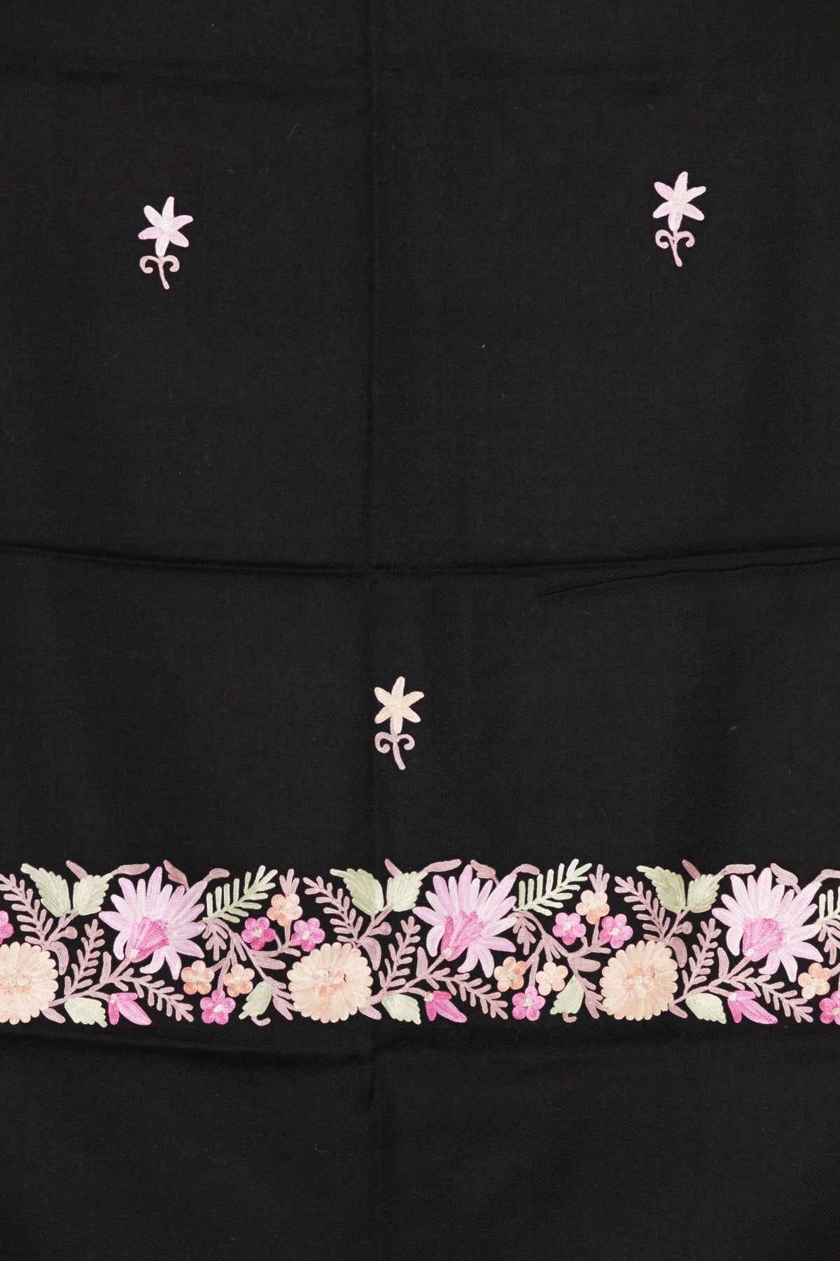 Flat detail of a black merino wool stole, with small Aari flower sprigs above a border of pink and cream flowers and pale green leaves.