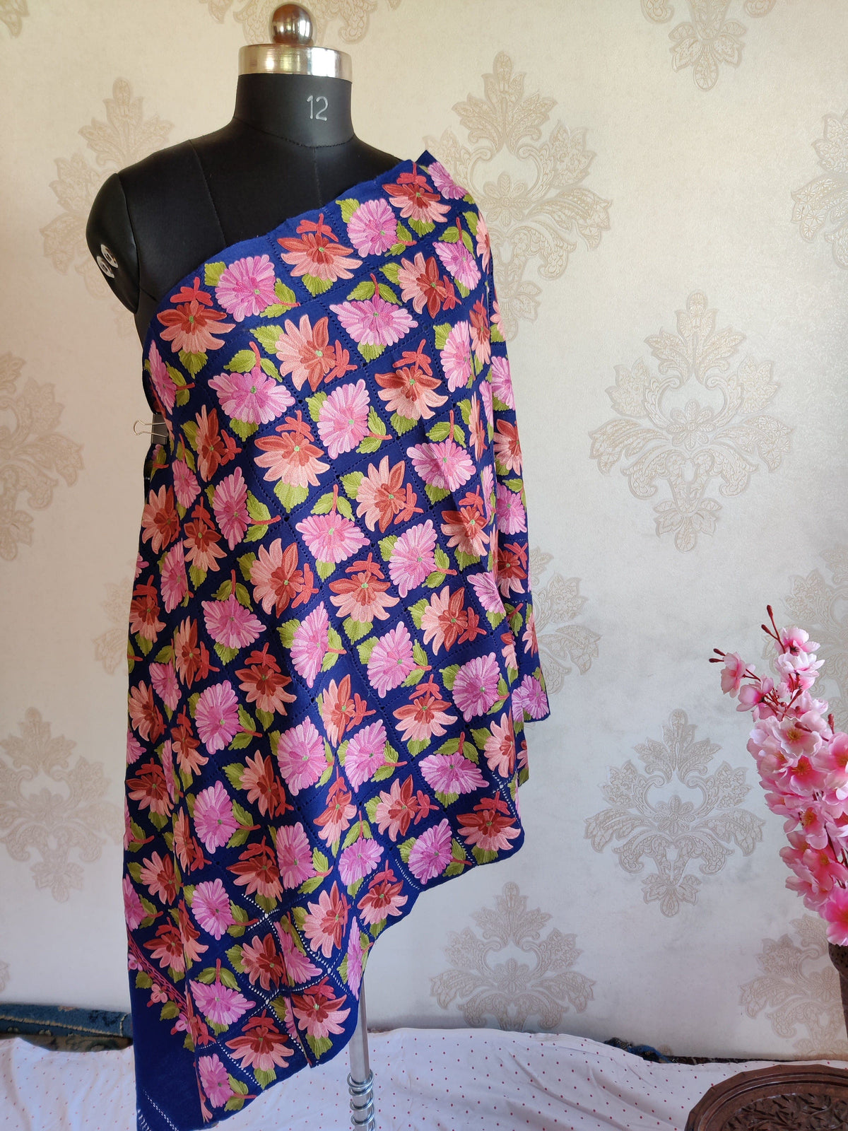 Full-length royal-blue Merino wool scarf draped on a mannequin, with a grid of pink flowers and a plain blue end
