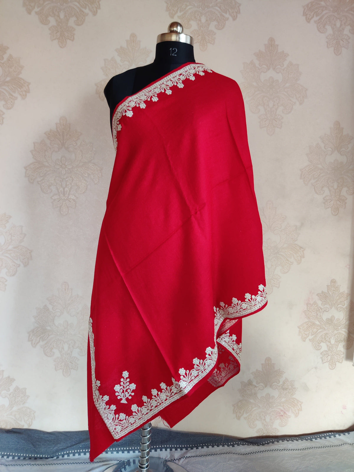Red merino wool stole draped on a mannequin, with silver-toned Tilla floral borders and separate corner motifs