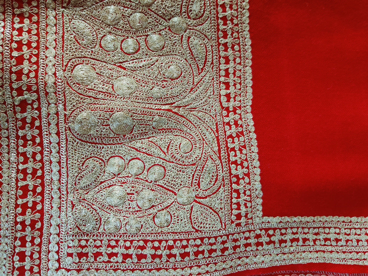 Flat corner detail of a red Merino wool stole, with pale metallic Tilla paisleys meeting narrow floral side trim