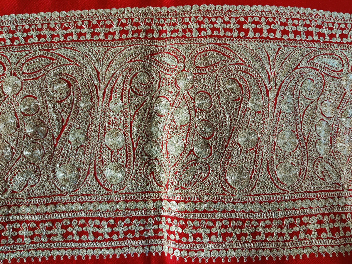 Close-up of repeating pale metallic Tilla paisleys and small round motifs along the red Merino wool stole's broad border