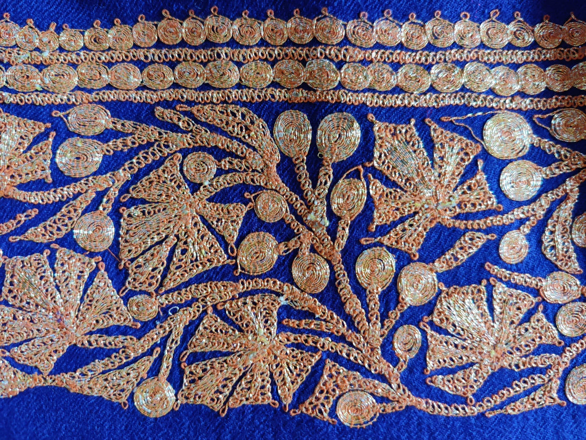 Close-up of gold-toned maple leaves and curling stems embroidered along the blue stole border.