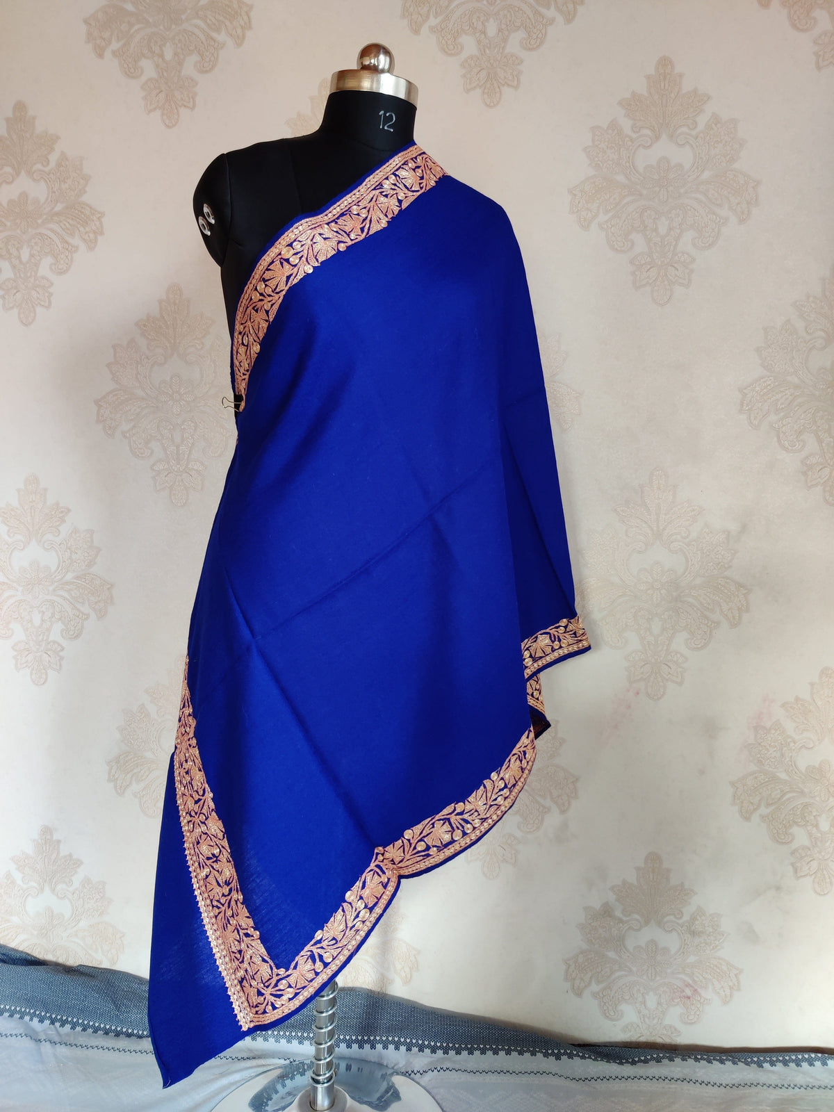 Full view of a royal-blue stole draped on a mannequin, showing a plain centre framed by gold-toned leafy embroidery.