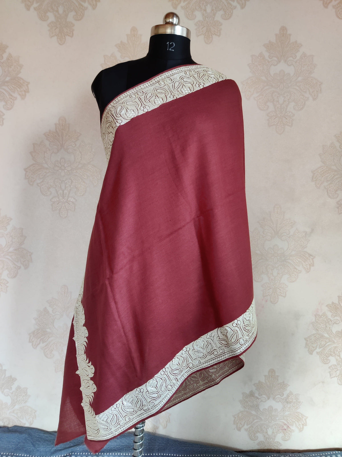 Full view of a reddish-brown stole draped on a mannequin, showing a plain centre and broad silver-toned paisley border.