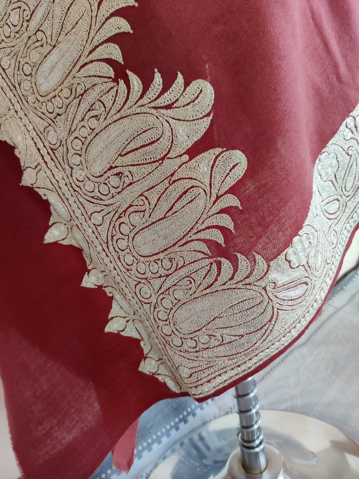 Draped corner of the reddish-brown stole with a broad silver-toned paisley and scrolling border.