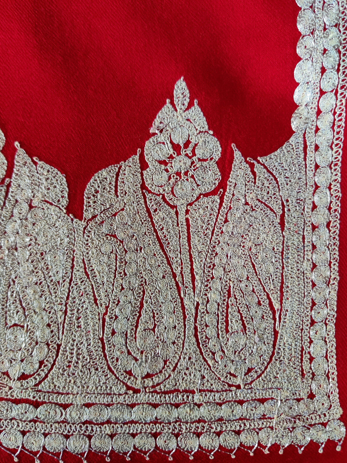 Corner close-up of red Merino wool scarf with large silver-toned Tilla paisley and floral motifs along the end border