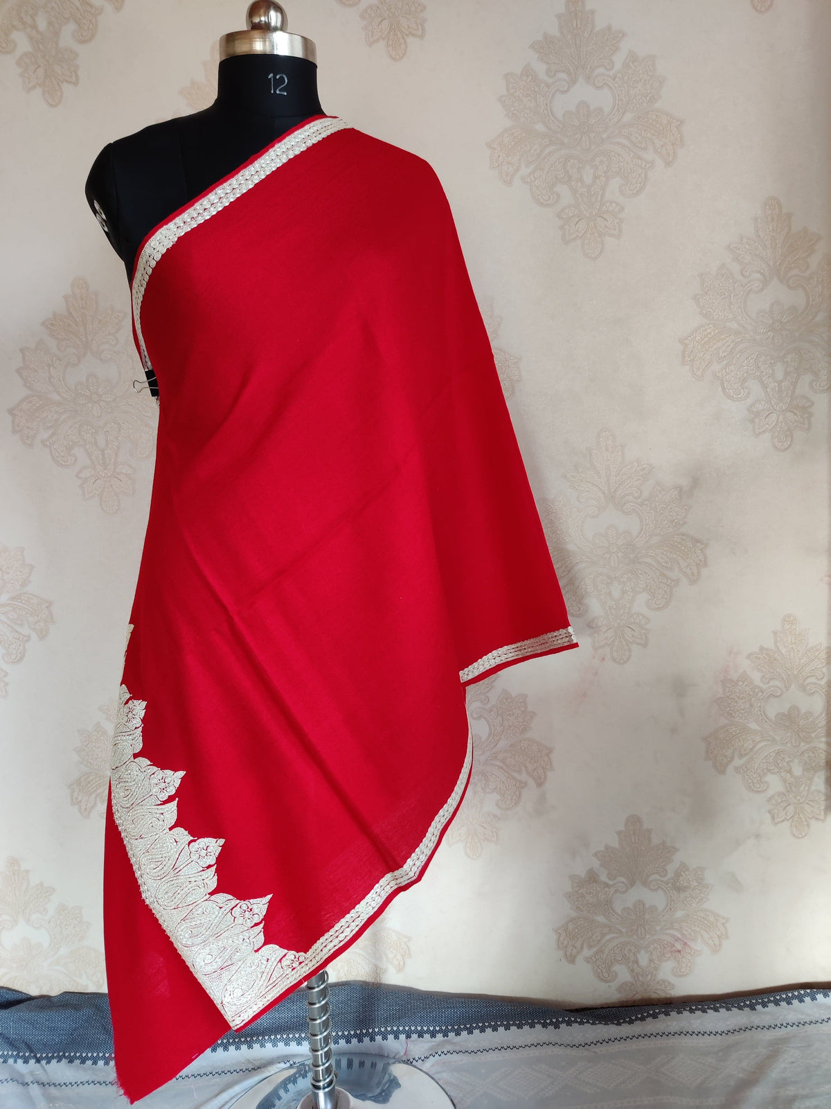 Full-length red Merino wool scarf draped on a mannequin, with a broad silver-toned paisley end border and narrow side trim