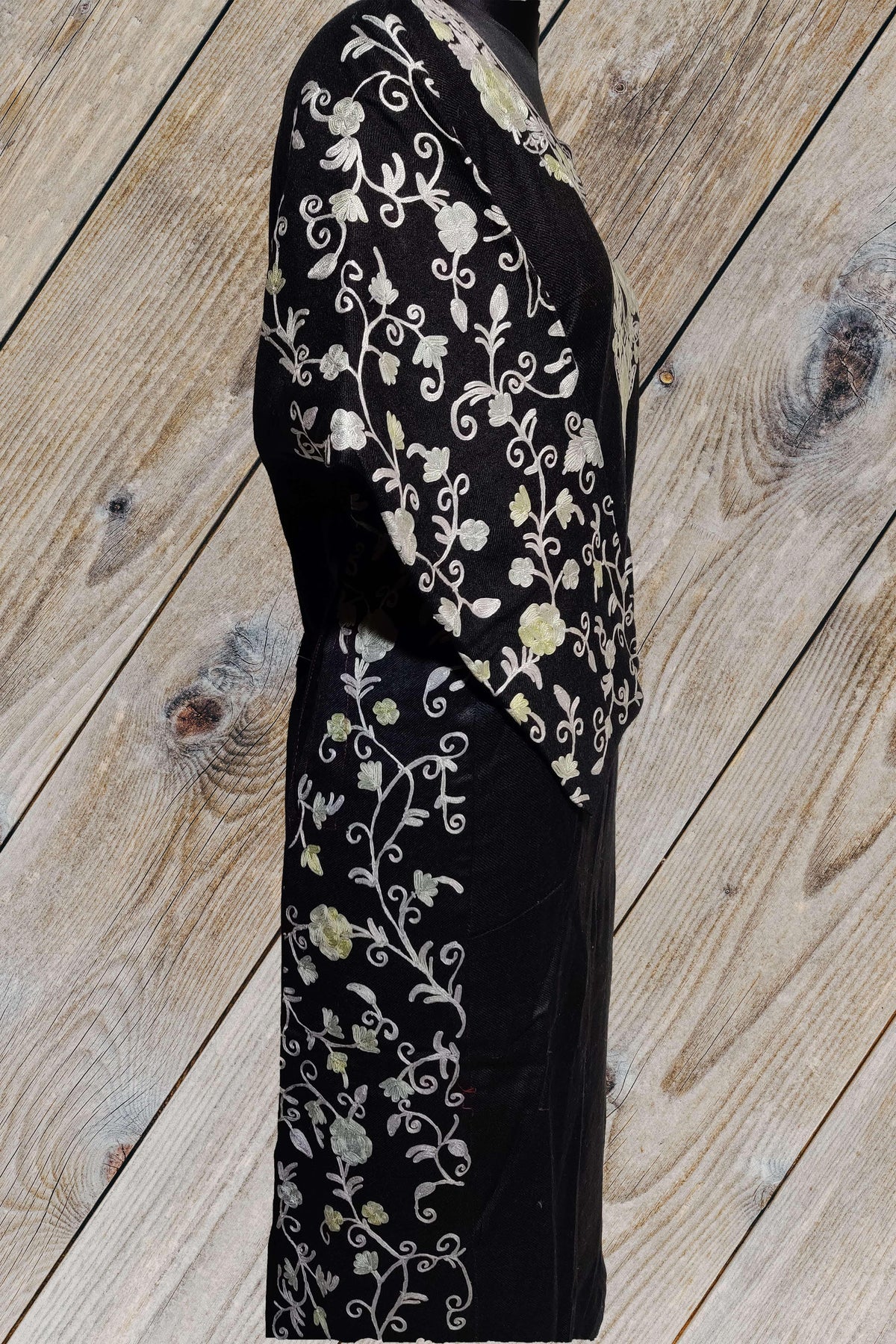 Side view of a black pheran showing cream Aari floral vines down the sleeve and along the side of the garment