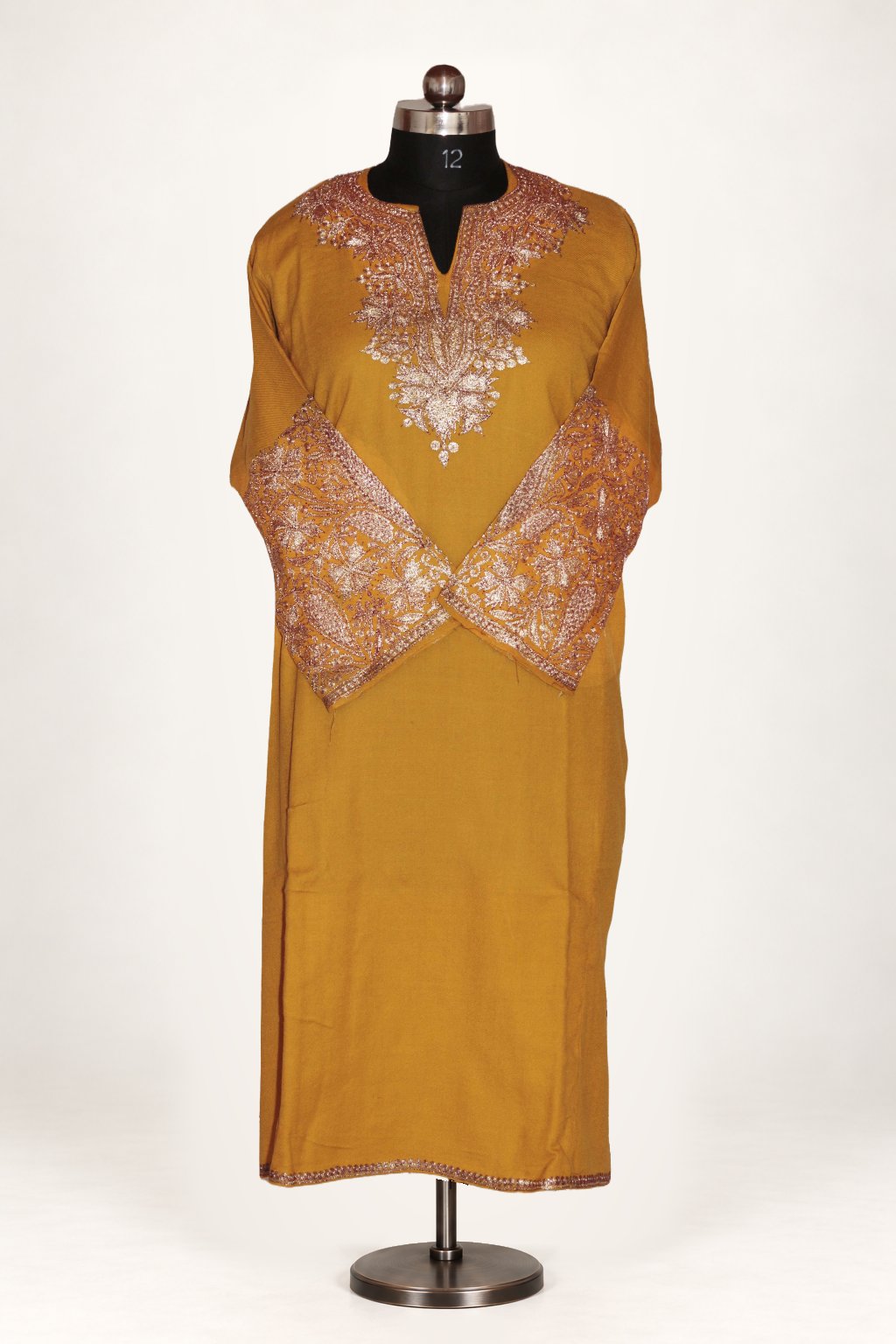 Mustard pheran on a mannequin, with pale floral Tilla embroidery around the neckline and crossed cuffs