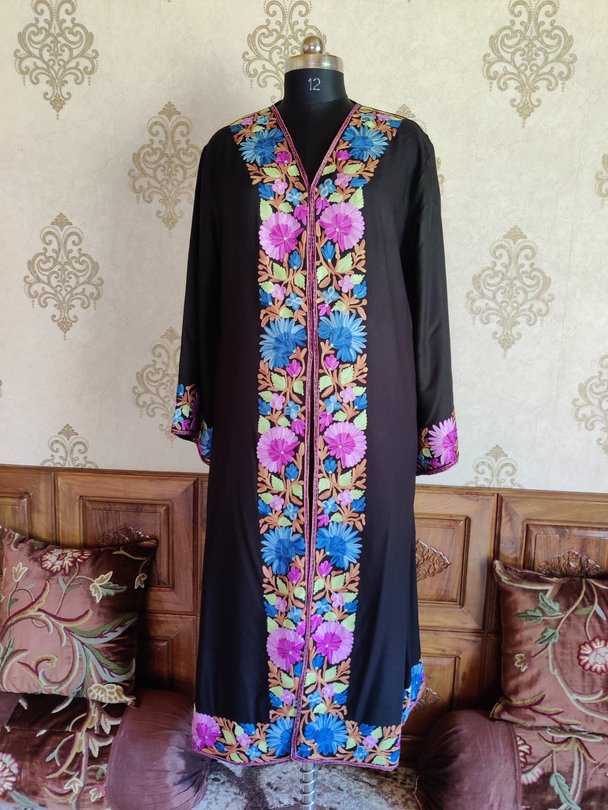 Full front view of a black robe with sleeves lowered and blue and purple floral borders along the opening, cuffs and hem.
