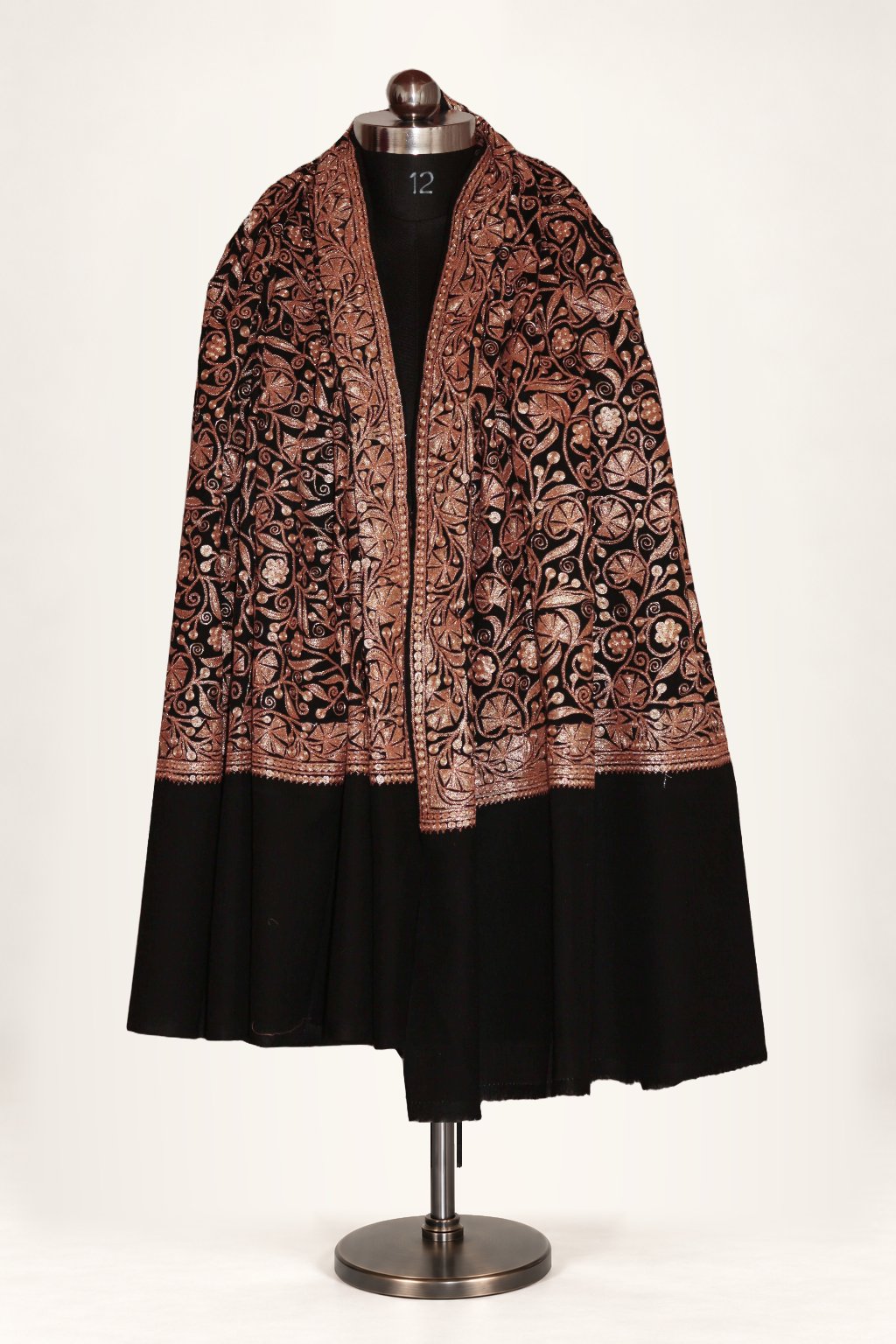 Black merino wool shawl draped over both shoulders of a mannequin, with copper-toned Tilla floral vines above wide plain ends.