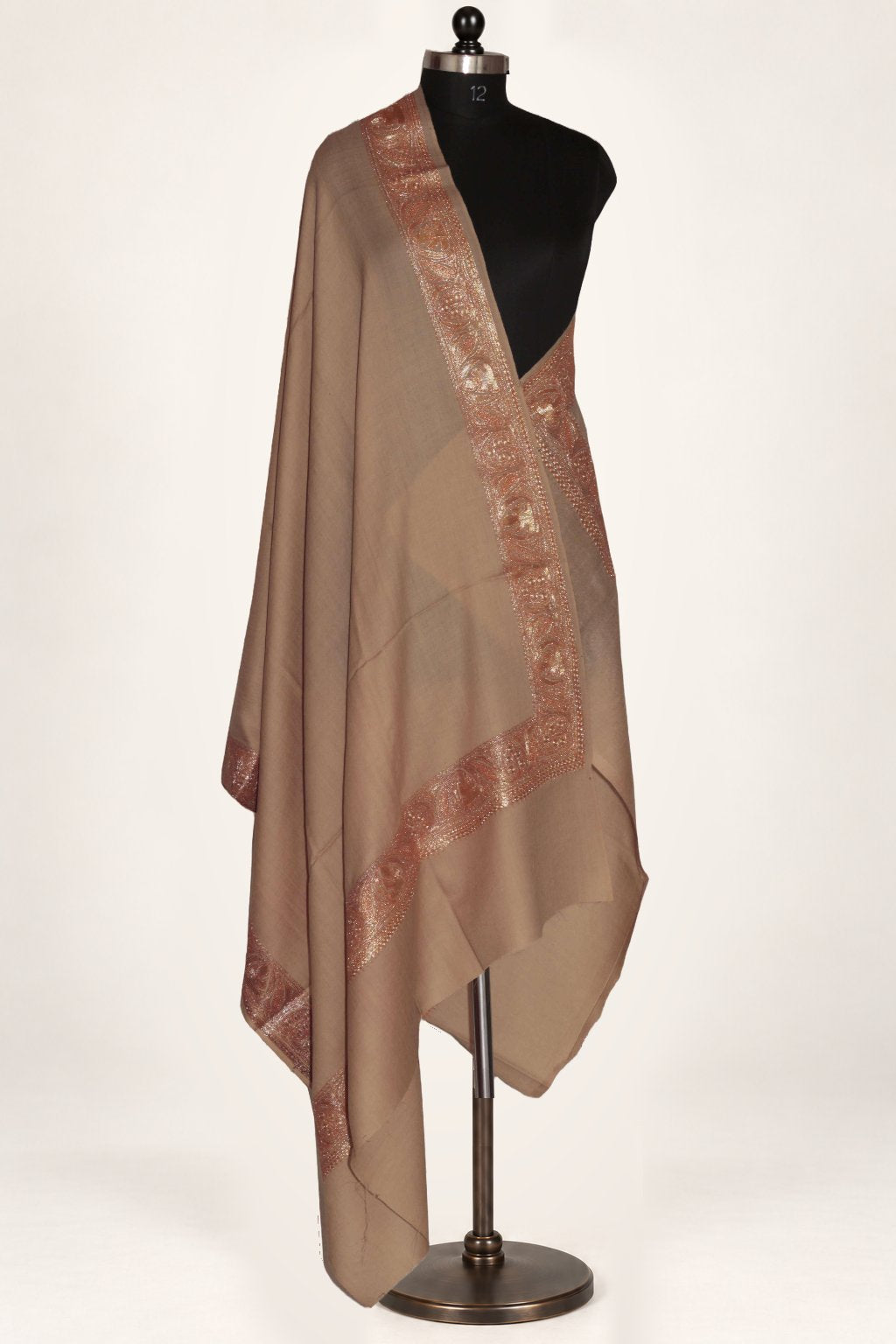 Beige merino wool shawl draped around a mannequin, with broad copper-toned Tilla floral borders