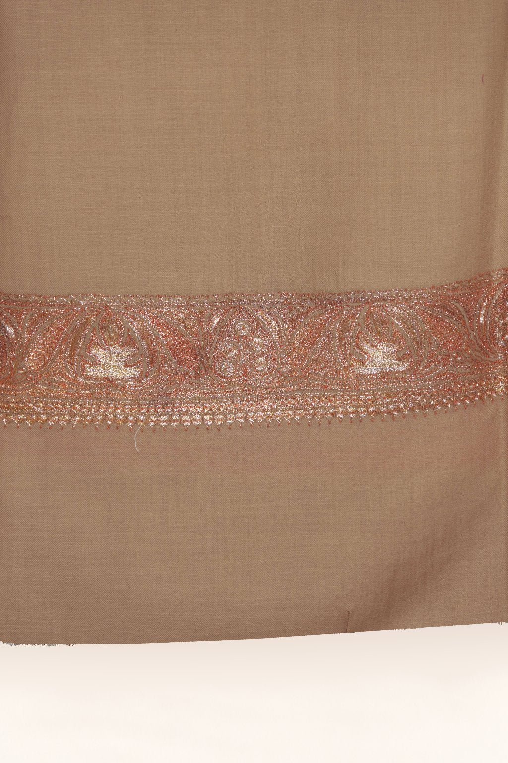 End detail of beige Merino wool shawl with a narrow peach-gold floral Tilla embroidered border above a plain hem