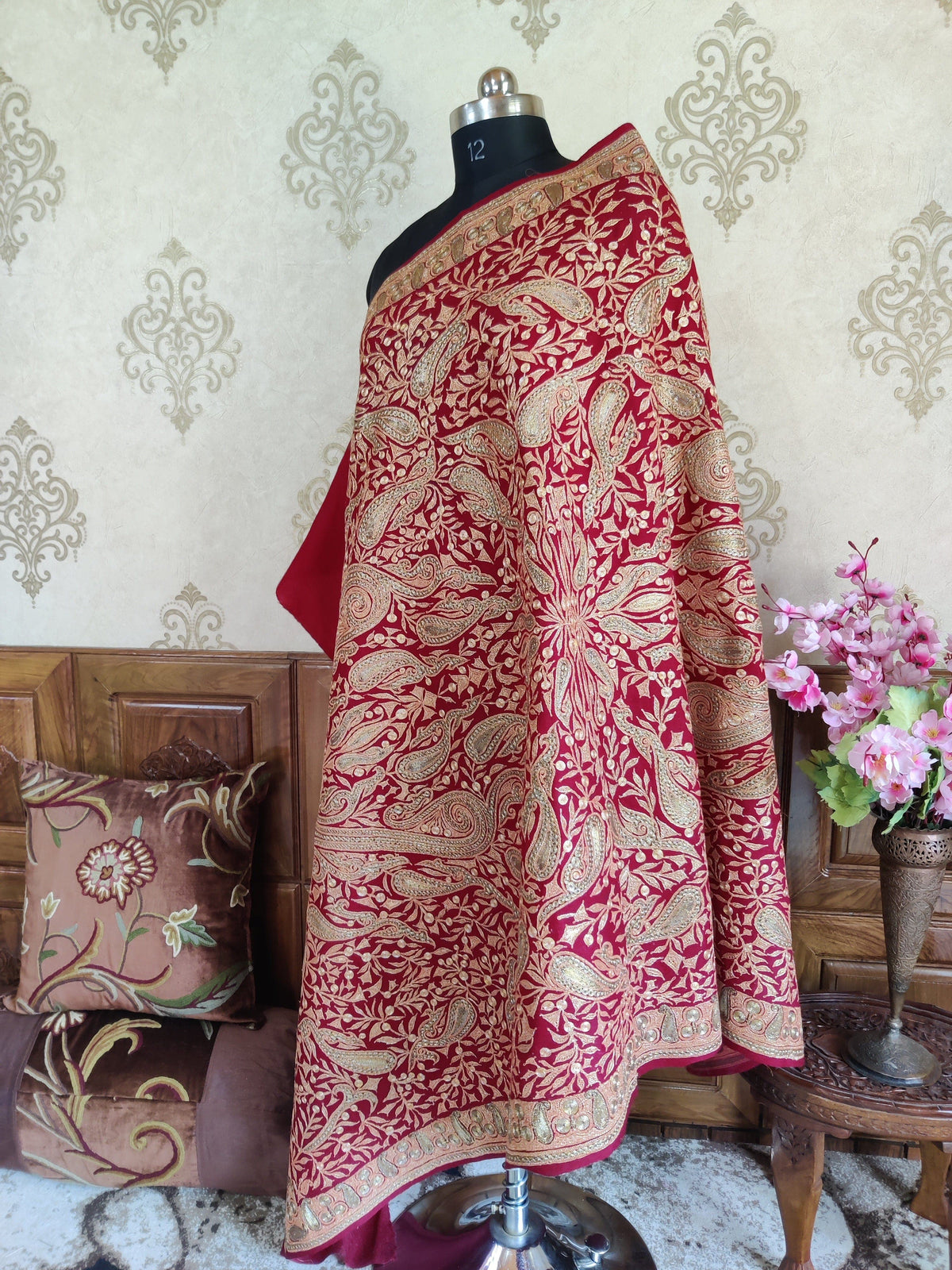 Maroon Merino wool shawl loosely draped over a mannequin, revealing large symmetrical Tilla paisley arrangements and patterned borders