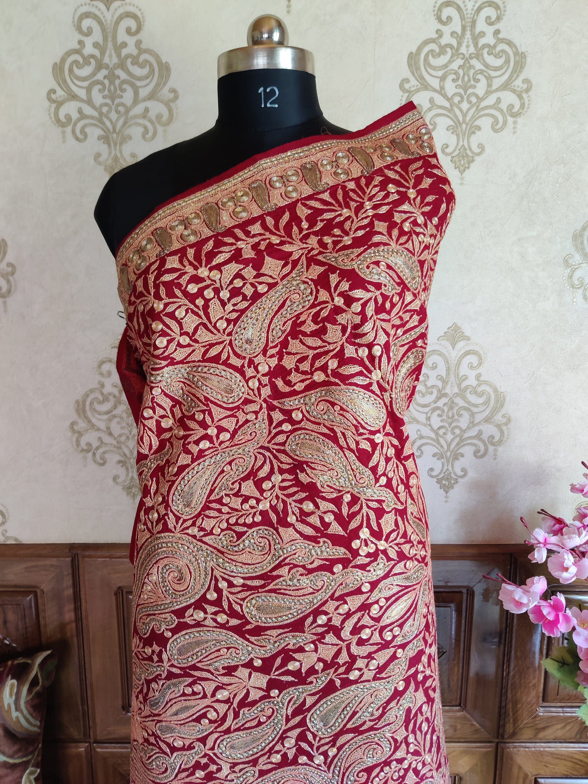 Upper view of a maroon Merino wool shawl wrapped on a mannequin, covered in pale metallic Tilla paisleys and leafy vines