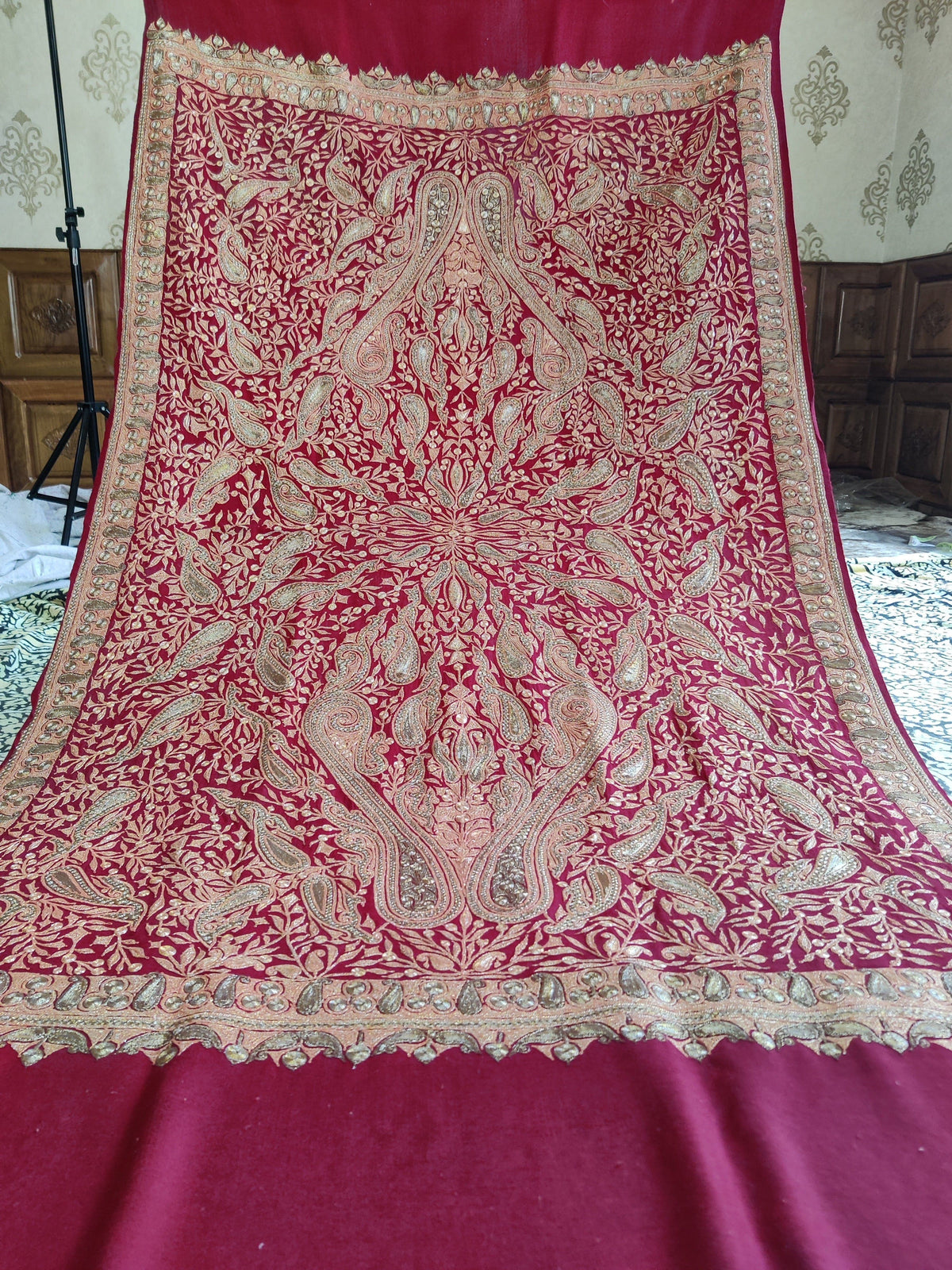 Maroon Merino wool shawl spread out, showing mirrored metallic Tilla paisleys and floral vines framed by borders and plain ends