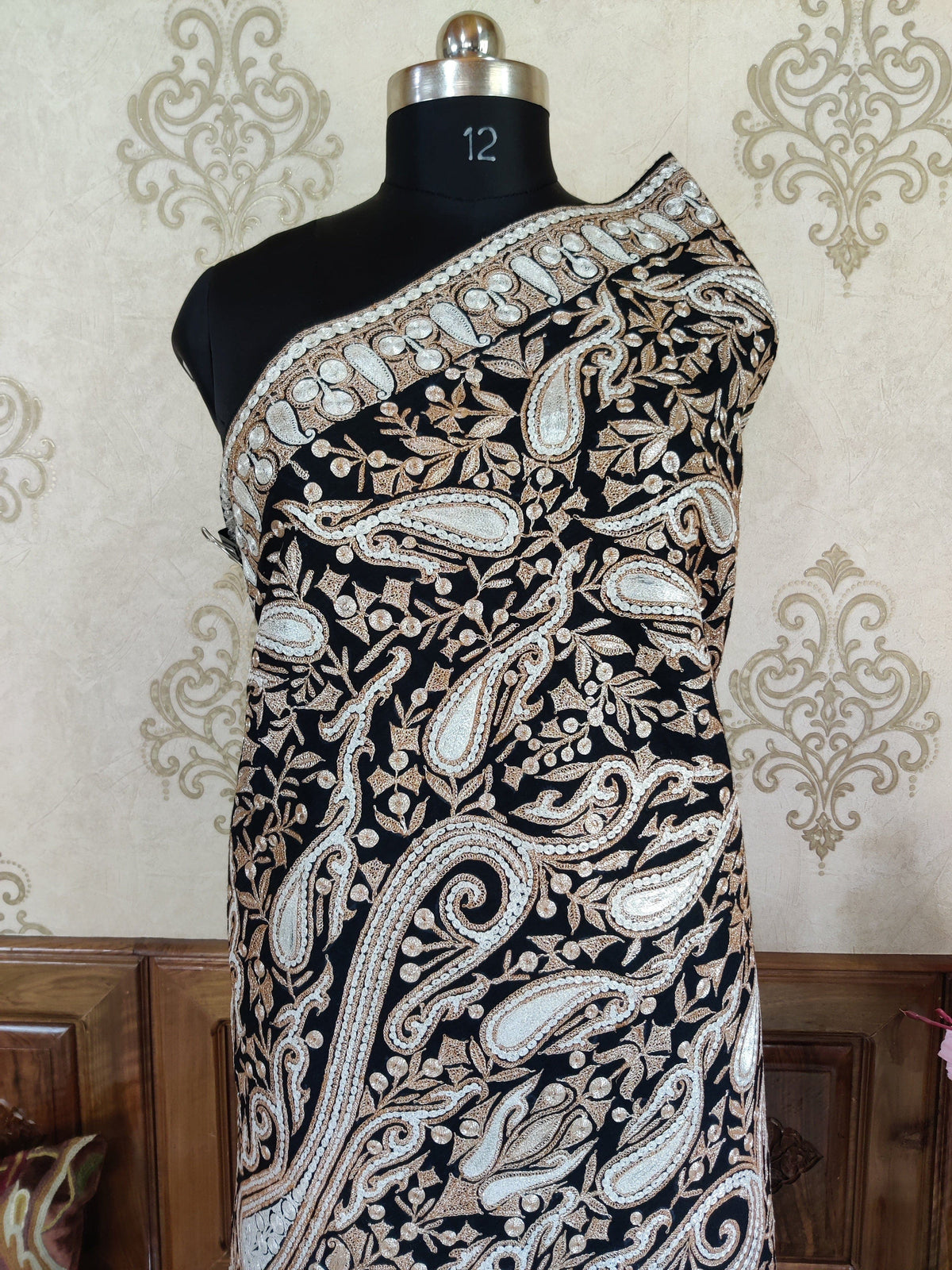 Torso view of the black Merino wool shawl wrapped around a mannequin, with paisley Tilla embroidery and a diagonal border