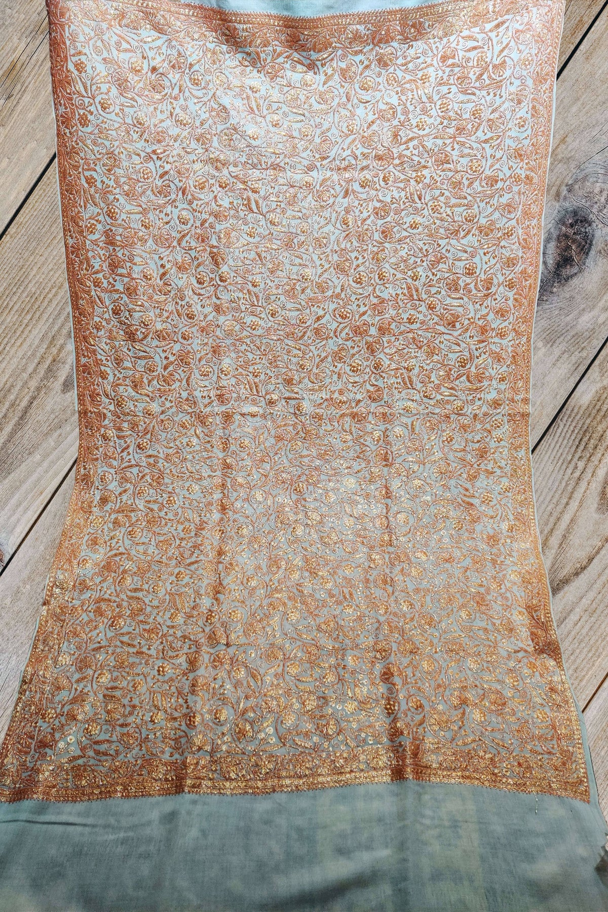 White Merino wool shawl spread flat, covered with golden-peach Tilla floral vines inside narrow embroidered borders