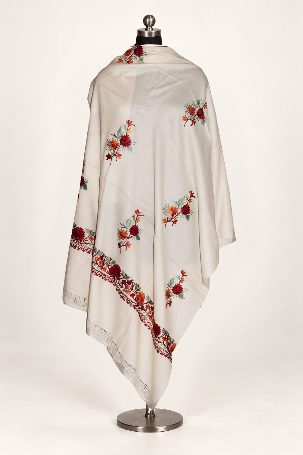 White merino wool shawl draped around a mannequin, with small red Aari flower sprays and a matching floral border