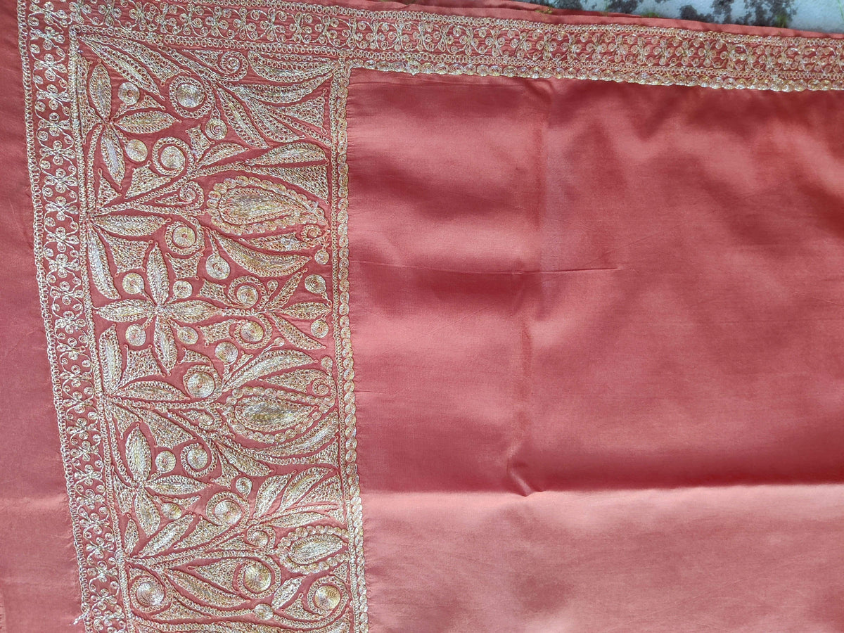 Coral-pink silk fabric corner with a broad pale-gold floral border and narrow scrolling edge.