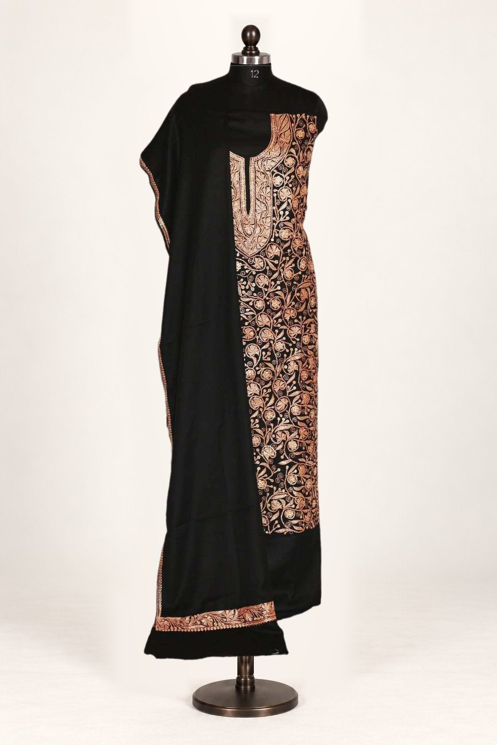 Black suit fabric displayed on a mannequin, with copper-toned Tilla embroidery at the neckline and along a long floral panel